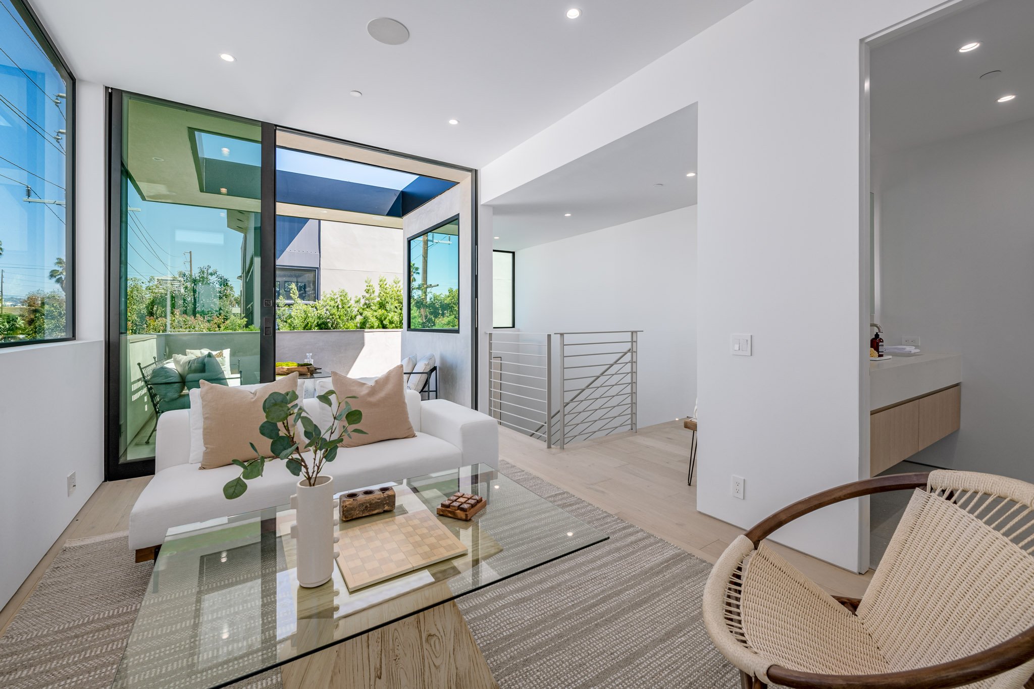 Bright indoor-outdoor lounge where expansive sliding glass doors create a seamless connection to a private terrace, built by JBurton General Contractor.