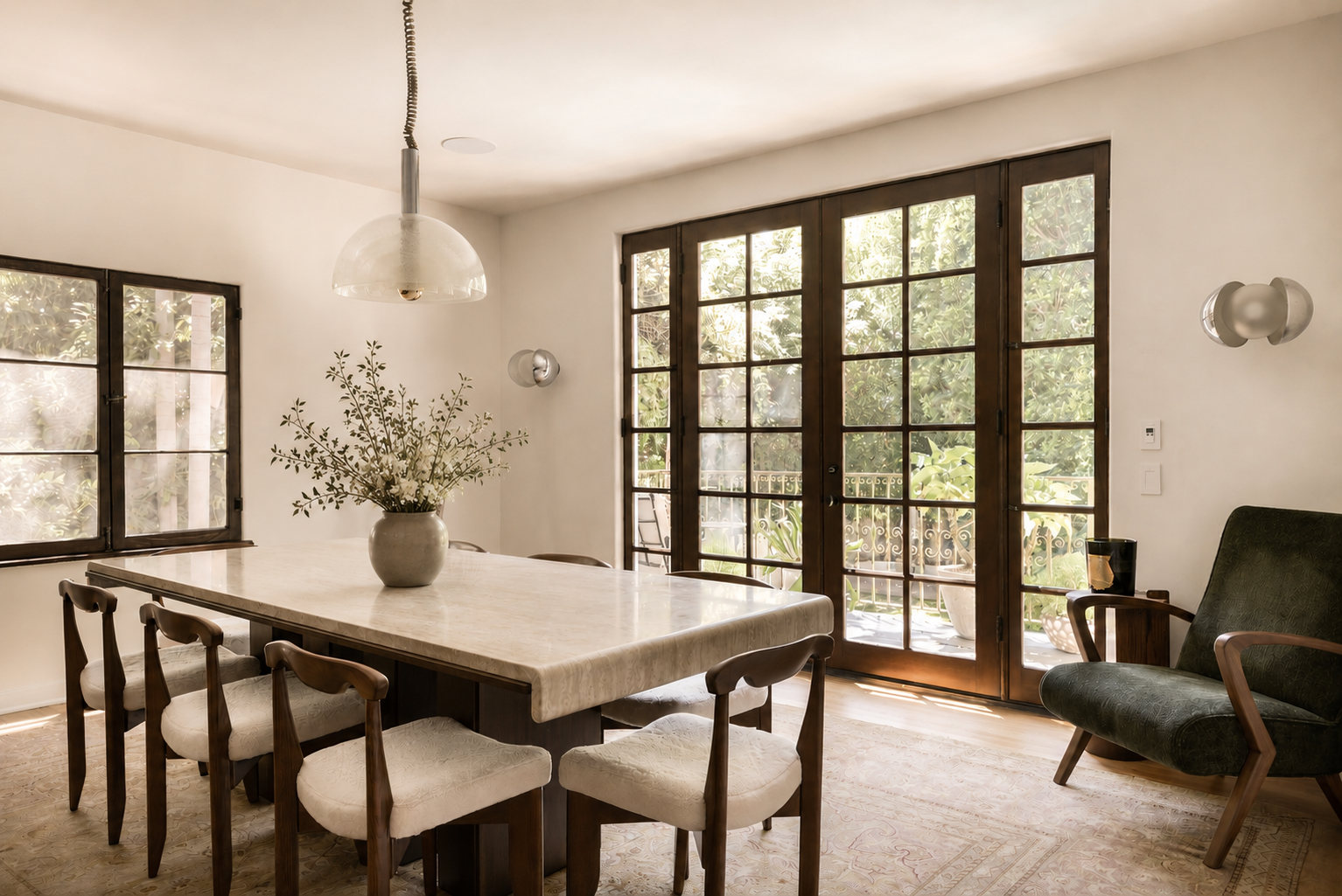 Elegant dining room with steel-framed doors, natural light, and indoor-outdoor living connections in a Los Feliz Spanish Revival home.