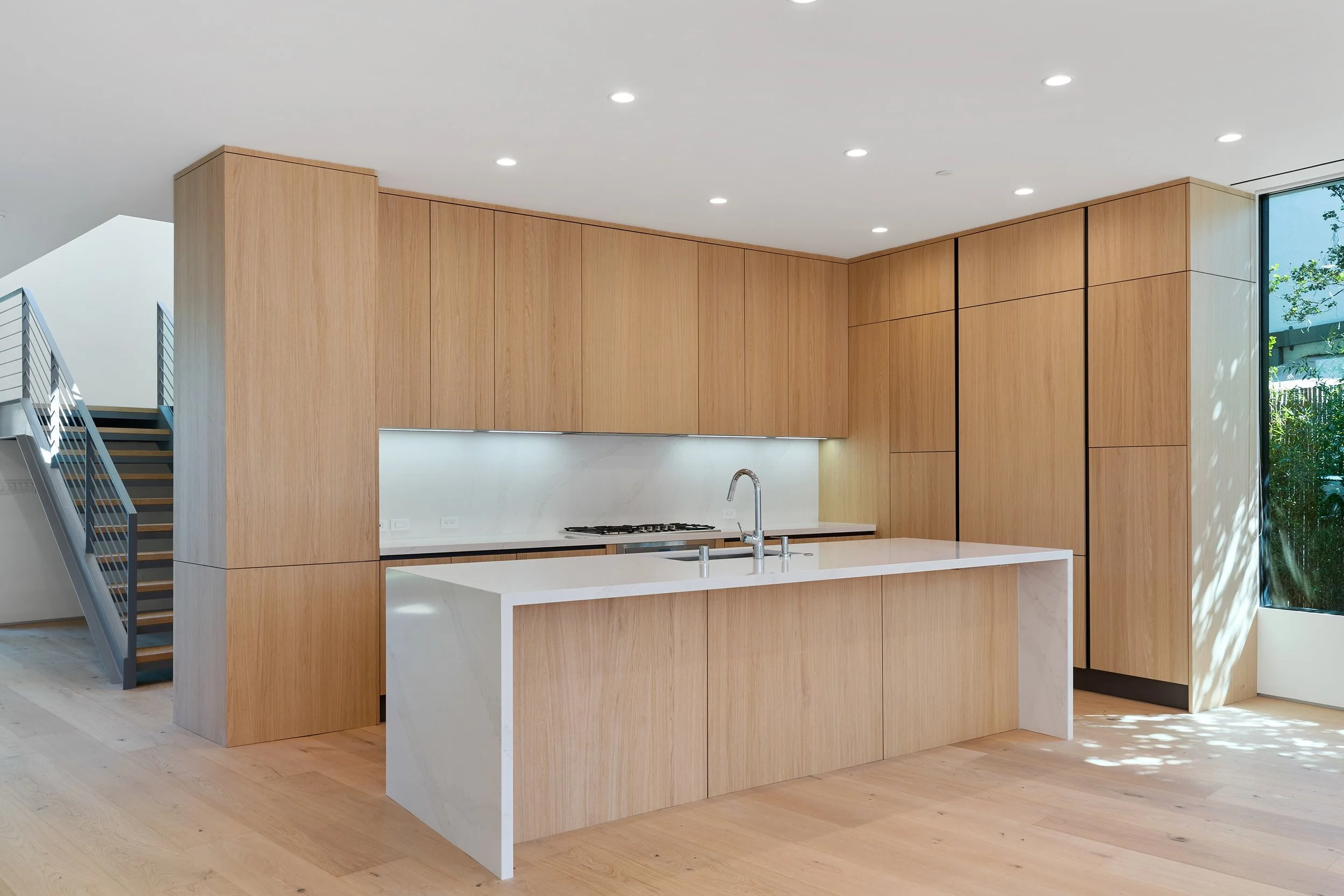 Custom kitchen featuring full-height white oak cabinetry, a waterfall quartz island, and clean minimalist detailing, constructed by JBurton General Contractor.