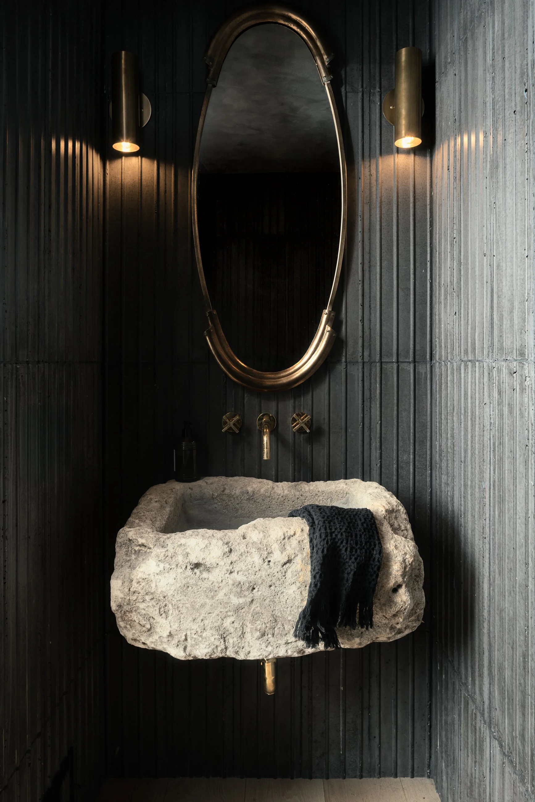 Sculptural stone vessel sink and custom textured wall finish in a contemporary powder room, remodel completed by JBurton General Contractor in Benedict Canyon, Los Angeles.