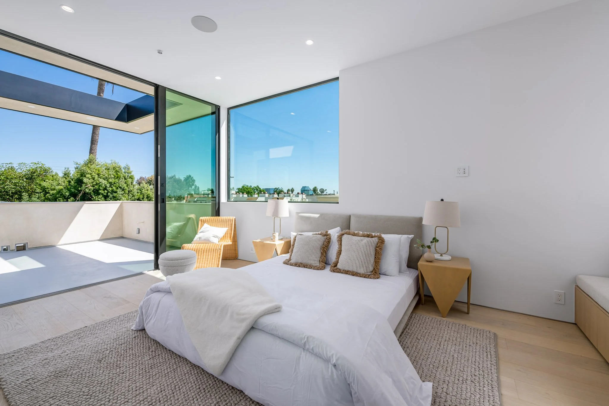Bright bedroom opening to a private terrace through expansive sliding glass doors, blending indoor comfort with outdoor living by JBurton General Contractor.