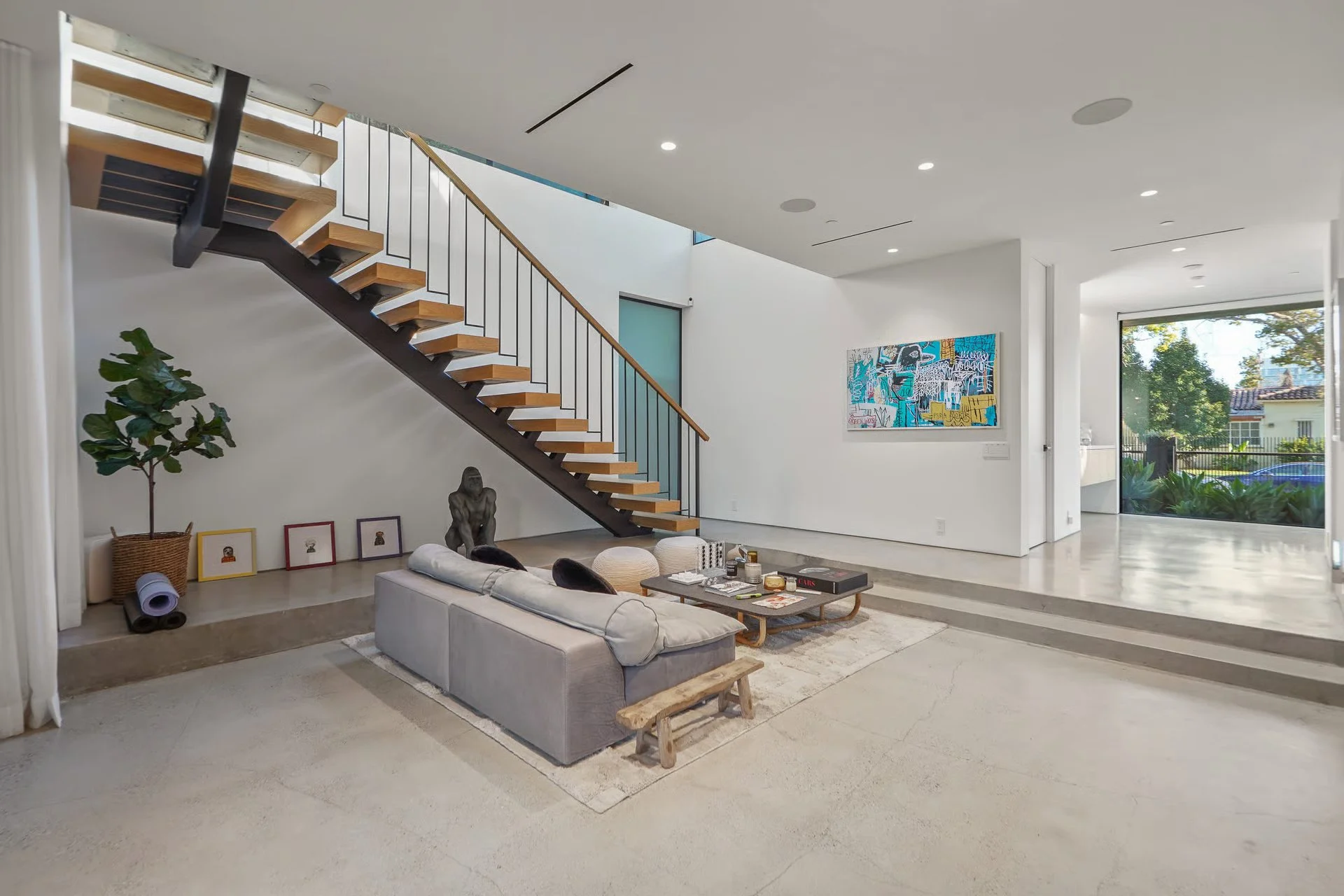 Modern floating staircase with wood treads and steel railing connecting the open-concept living areas, remodeled by JBurton General Contractor in Beverly Grove, Los Angeles.