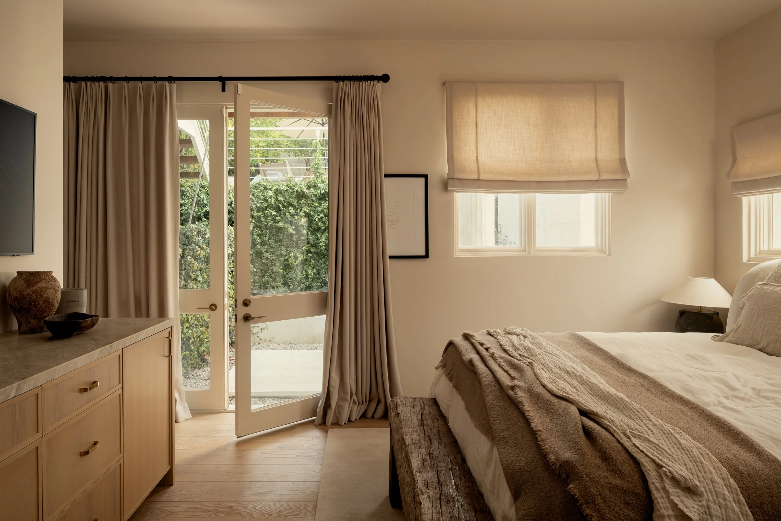 Contemporary primary bedroom with floor-to-ceiling doors, custom window treatments, and garden views, remodel completed by JBurton General Contractor in Benedict Canyon, Los Angeles.