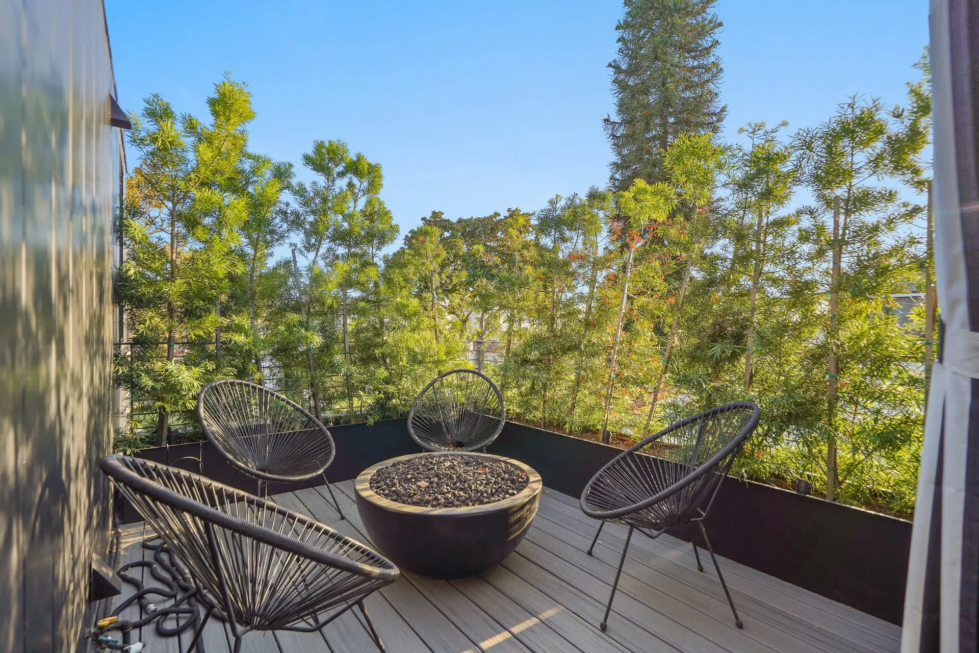 Private outdoor seating area with a contemporary fire pit and mature landscaping, designed as a relaxing retreat in this Beverly Grove home remodel by JBurton General Contractor.