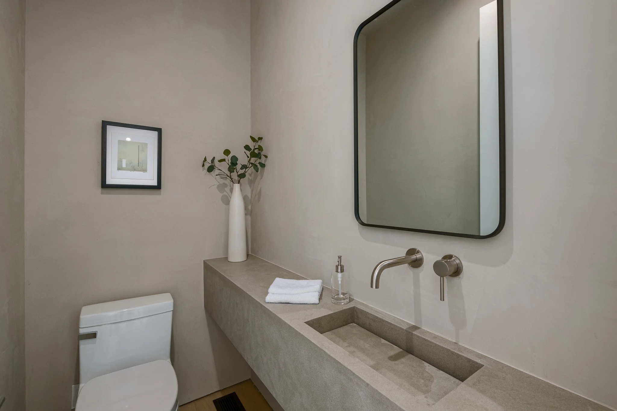 Minimalist powder room featuring a floating concrete vanity, wall-mounted faucet, and refined contemporary detailing by JBurton General Contractor.