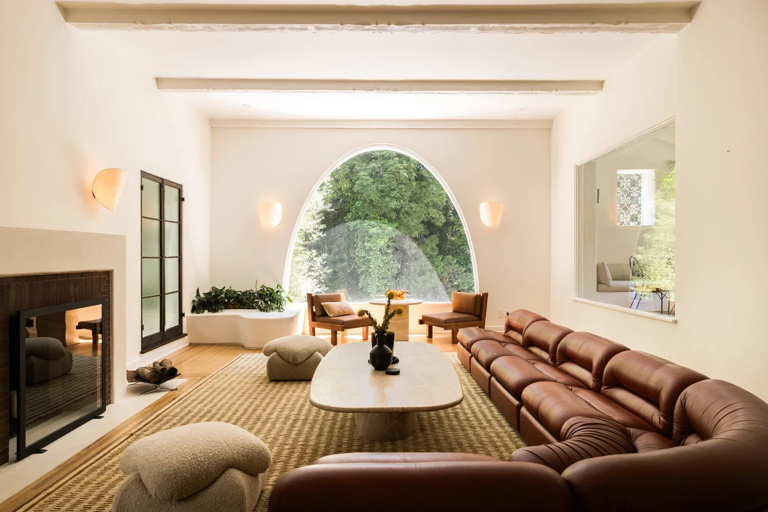 Spanish Revival living room renovation in Los Feliz featuring a dramatic arched picture window, custom plaster walls, and restored architectural details.