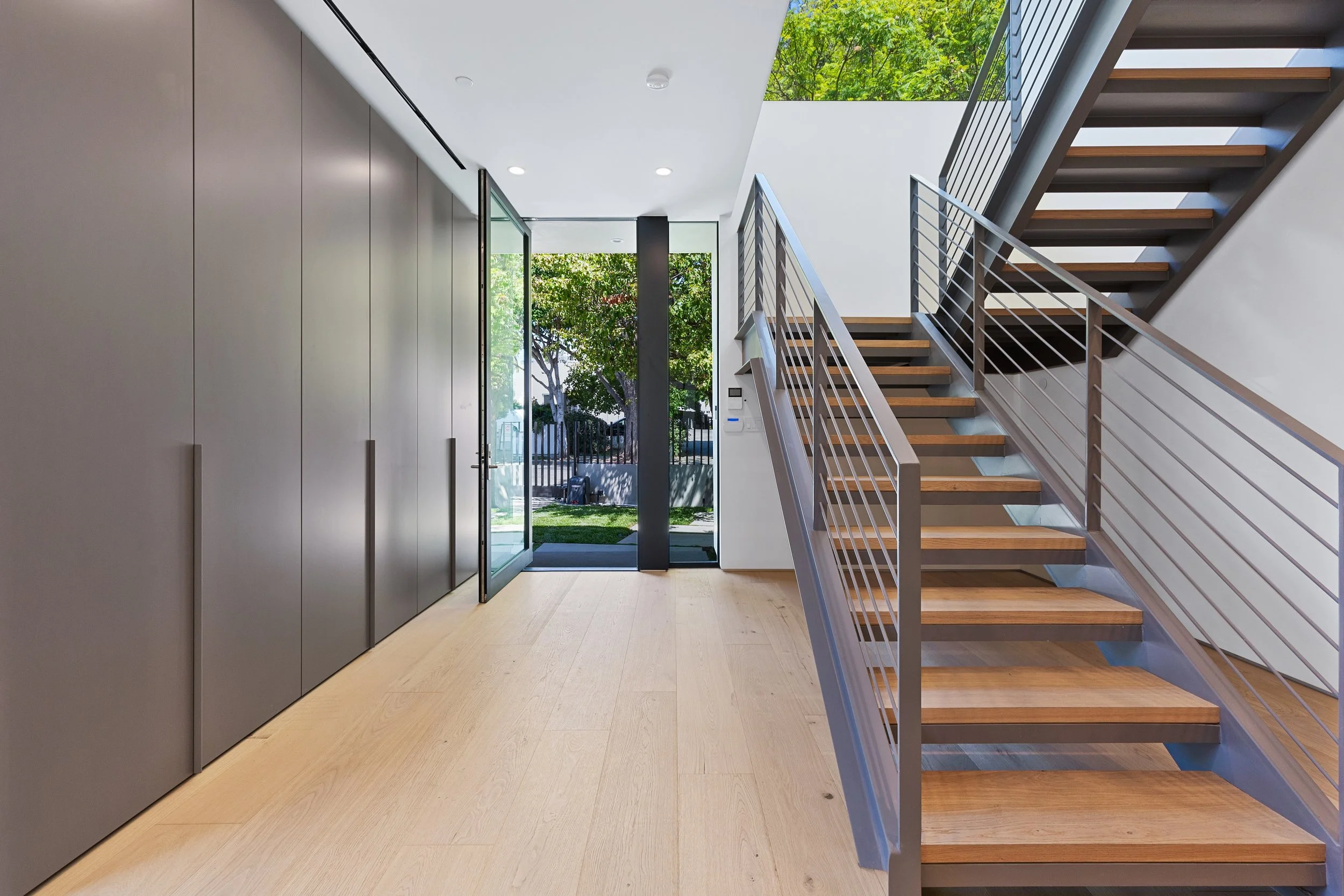 Welcoming entry featuring a custom oak staircase, full-height built-in storage, and abundant natural light, crafted by JBurton General Contractor in West Hollywood.