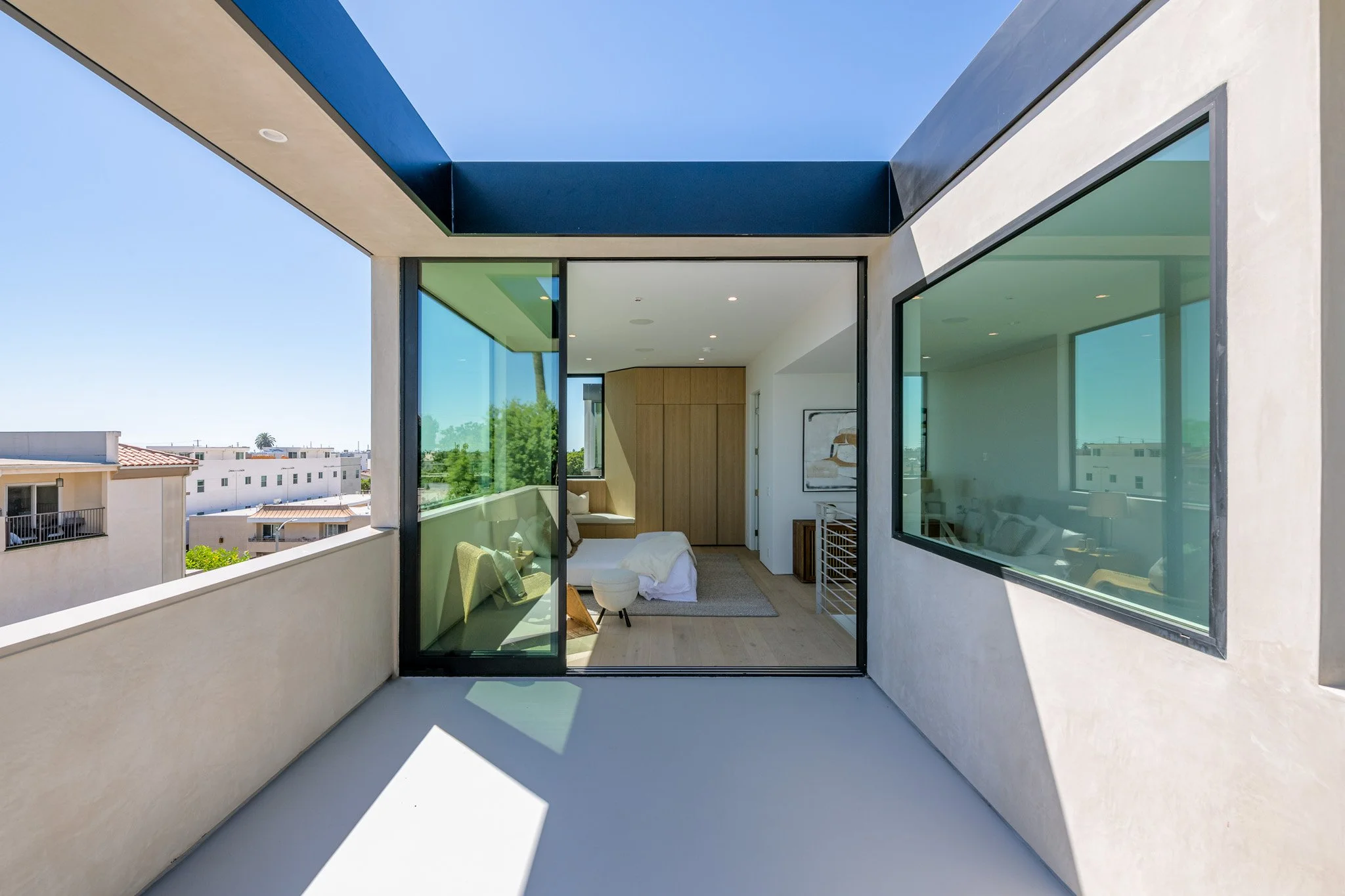 Private outdoor room framed by floor-to-ceiling glass and architectural overhangs, creating a seamless extension of the interior by JBurton General Contractor.
