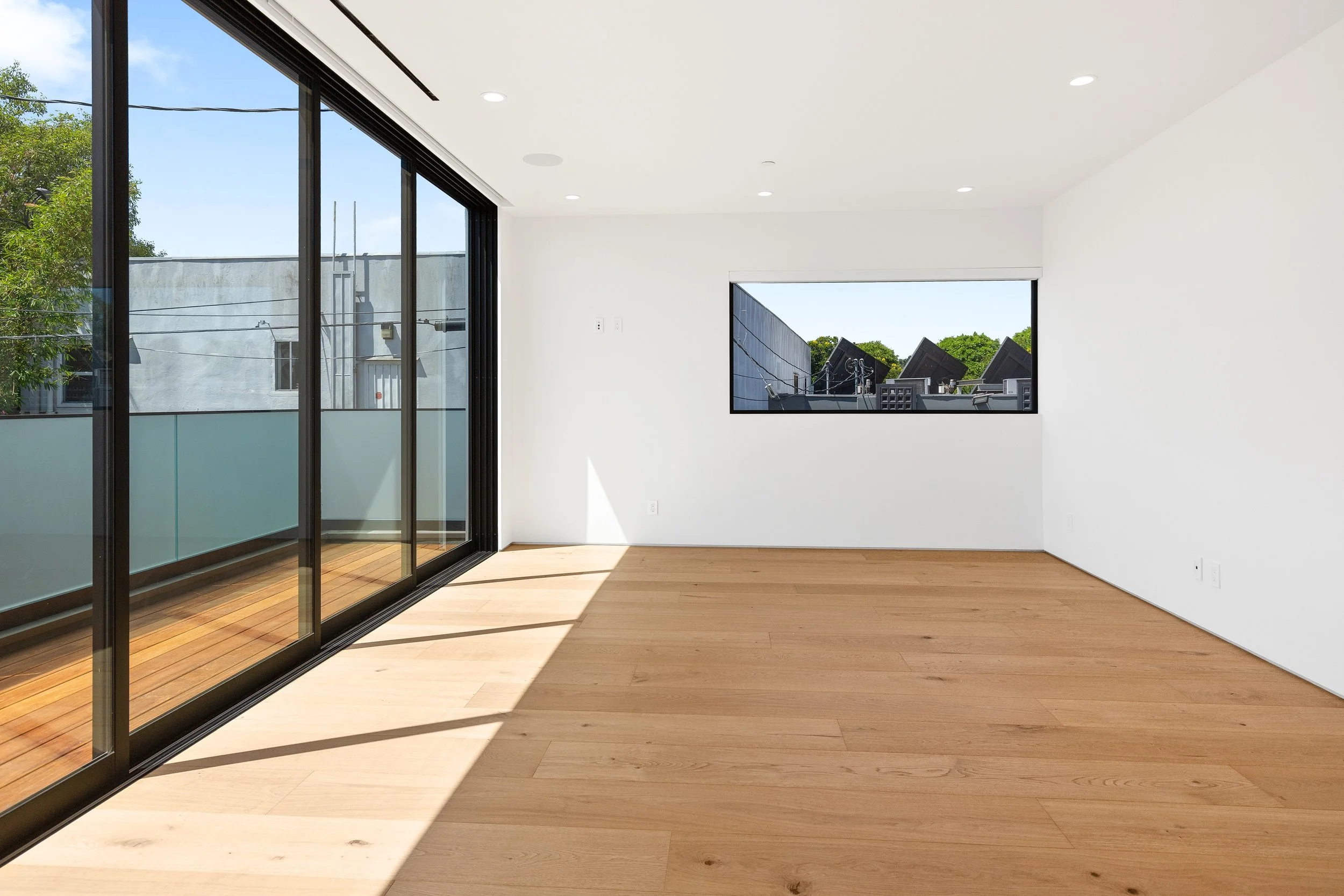 Sun-filled great room designed with expansive architectural glazing, wide-plank oak flooring, and flexible living spaces by JBurton General Contractor.