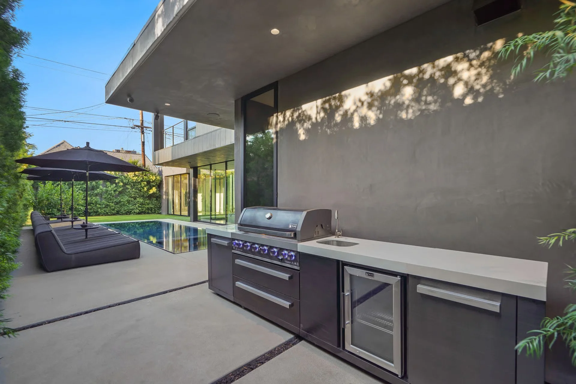 Custom outdoor kitchen with built-in grill, beverage refrigerator, and modern concrete finishes, remodeled by JBurton General Contractor in Beverly Grove, Los Angeles.