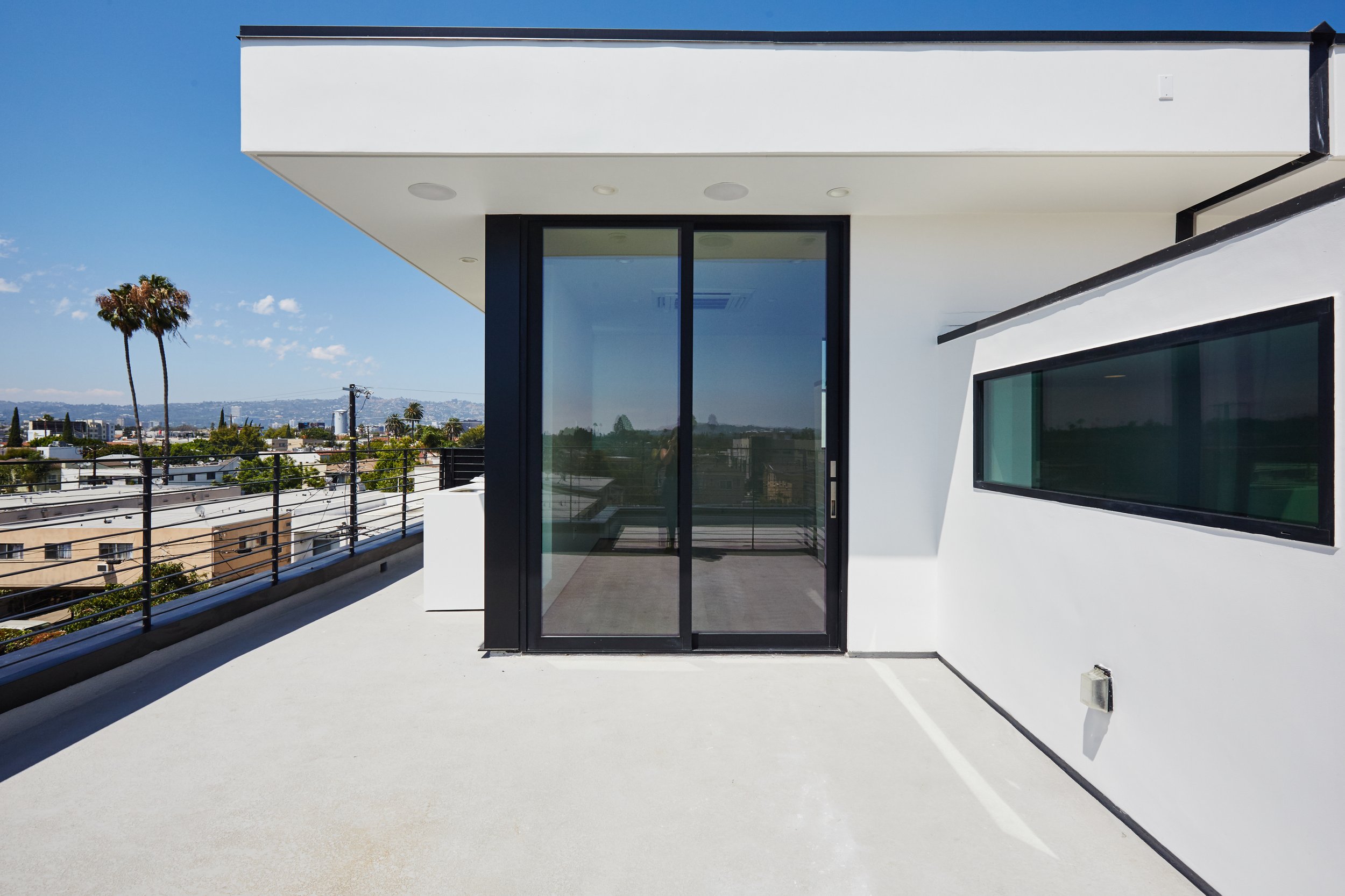 Private rooftop patio with large sliding glass doors and modern stucco exterior, constructed by JBurton General Contractor for a Faircrest Heights townhome.
