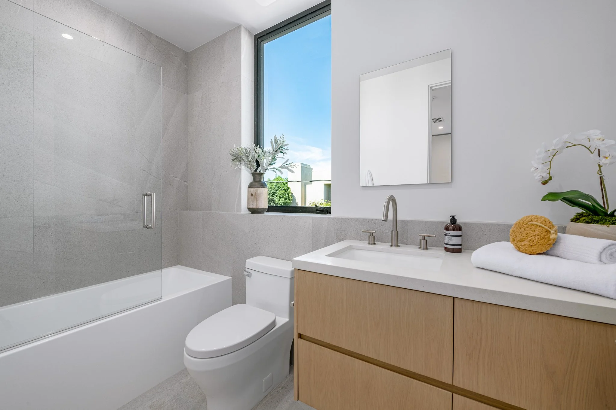 Family bathroom with a floating oak vanity, integrated storage, and timeless finishes that balance beauty and functionality, crafted by JBurton General Contractor.