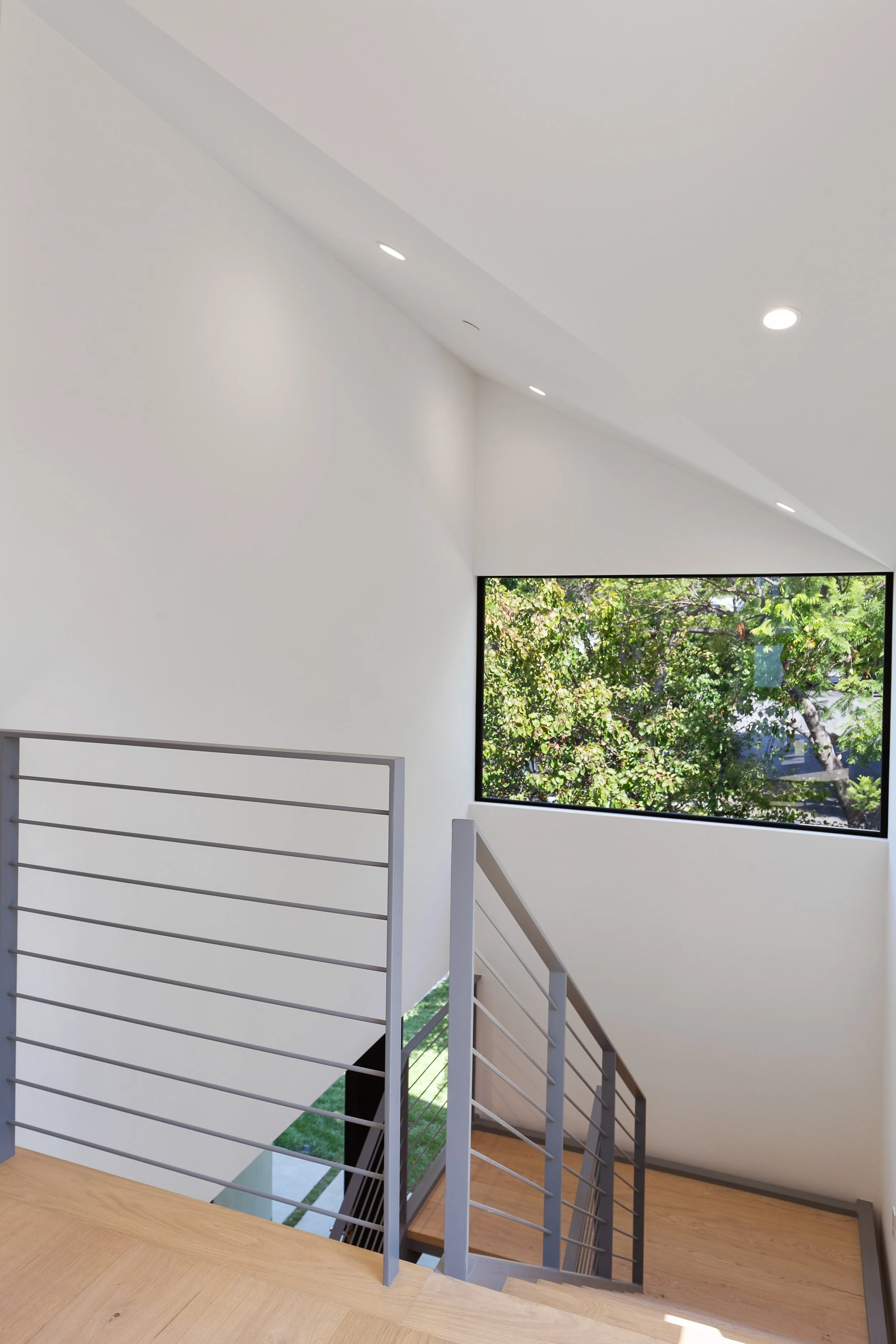 Sunlit upper stair landing designed with architectural glazing and clean contemporary detailing, built by JBurton General Contractor.