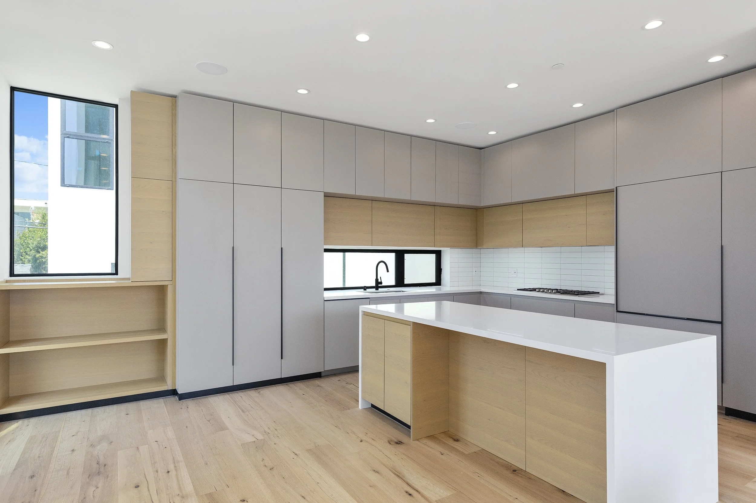 Modern kitchen in a newly built Faircrest Heights townhome featuring custom cabinetry, a waterfall island, and white quartz countertops.
