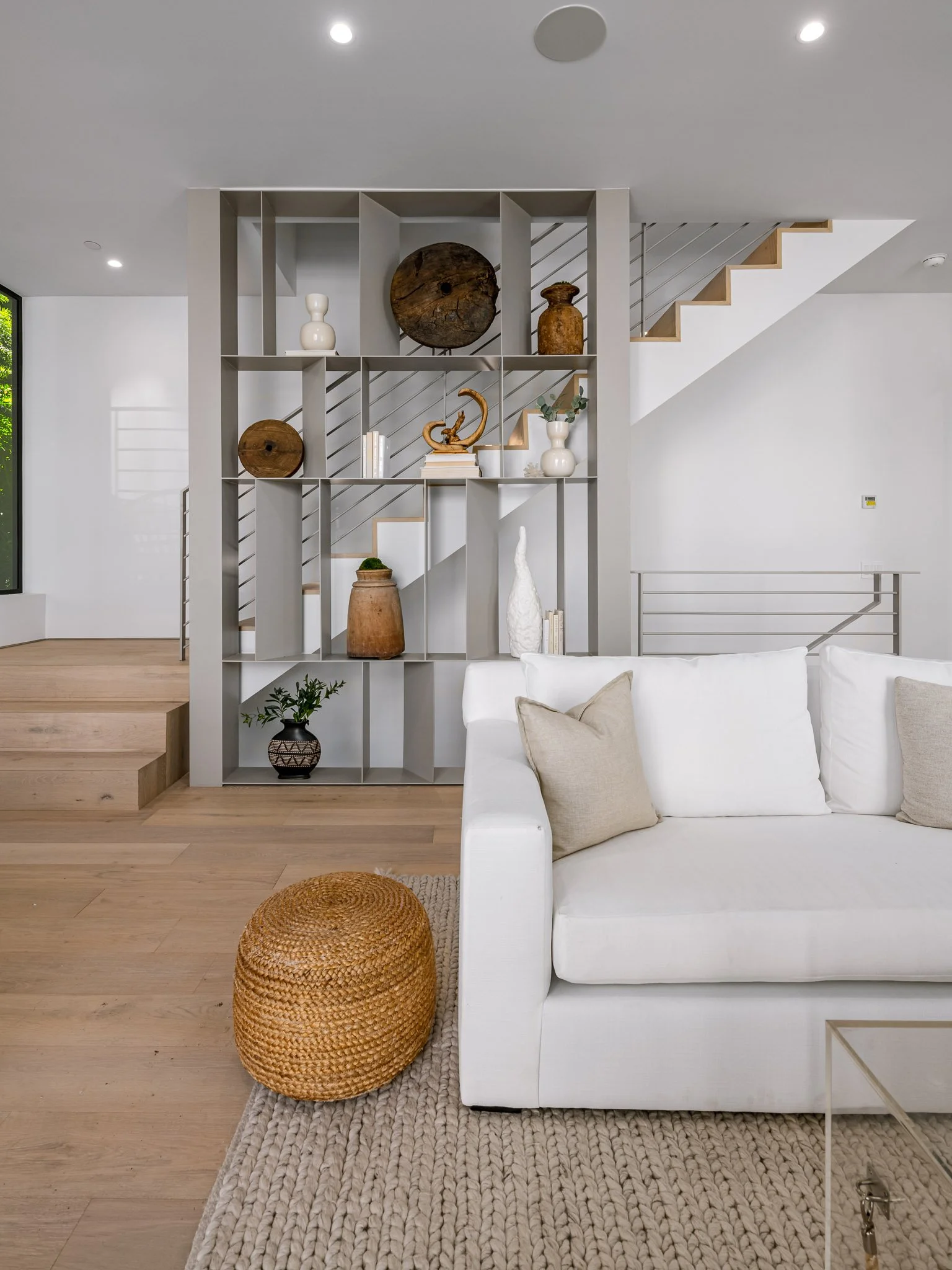Living area featuring a custom open shelving partition that creates visual separation while maintaining an open, light-filled floor plan by JBurton General Contractor.