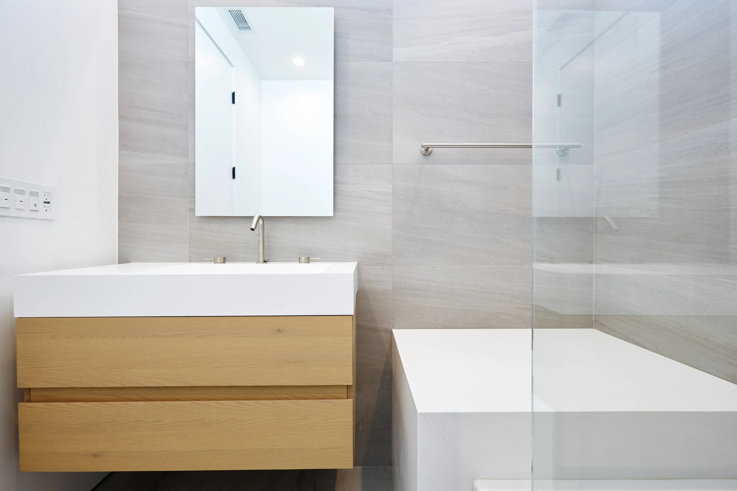 Modern bathroom featuring a floating wood vanity, integrated sink, and large-format porcelain tile, completed by JBurton General Contractor in Faircrest Heights.