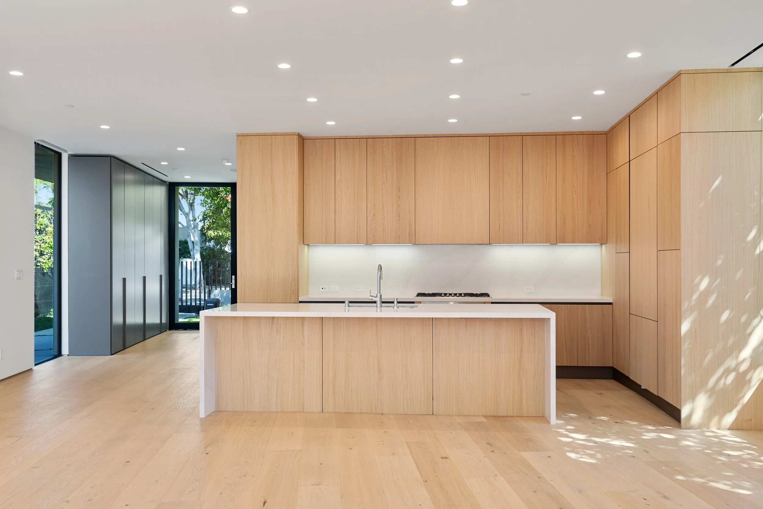 Minimalist kitchen showcasing furniture-inspired oak cabinetry, integrated appliances, and a spacious island designed for everyday living by JBurton General Contractor.