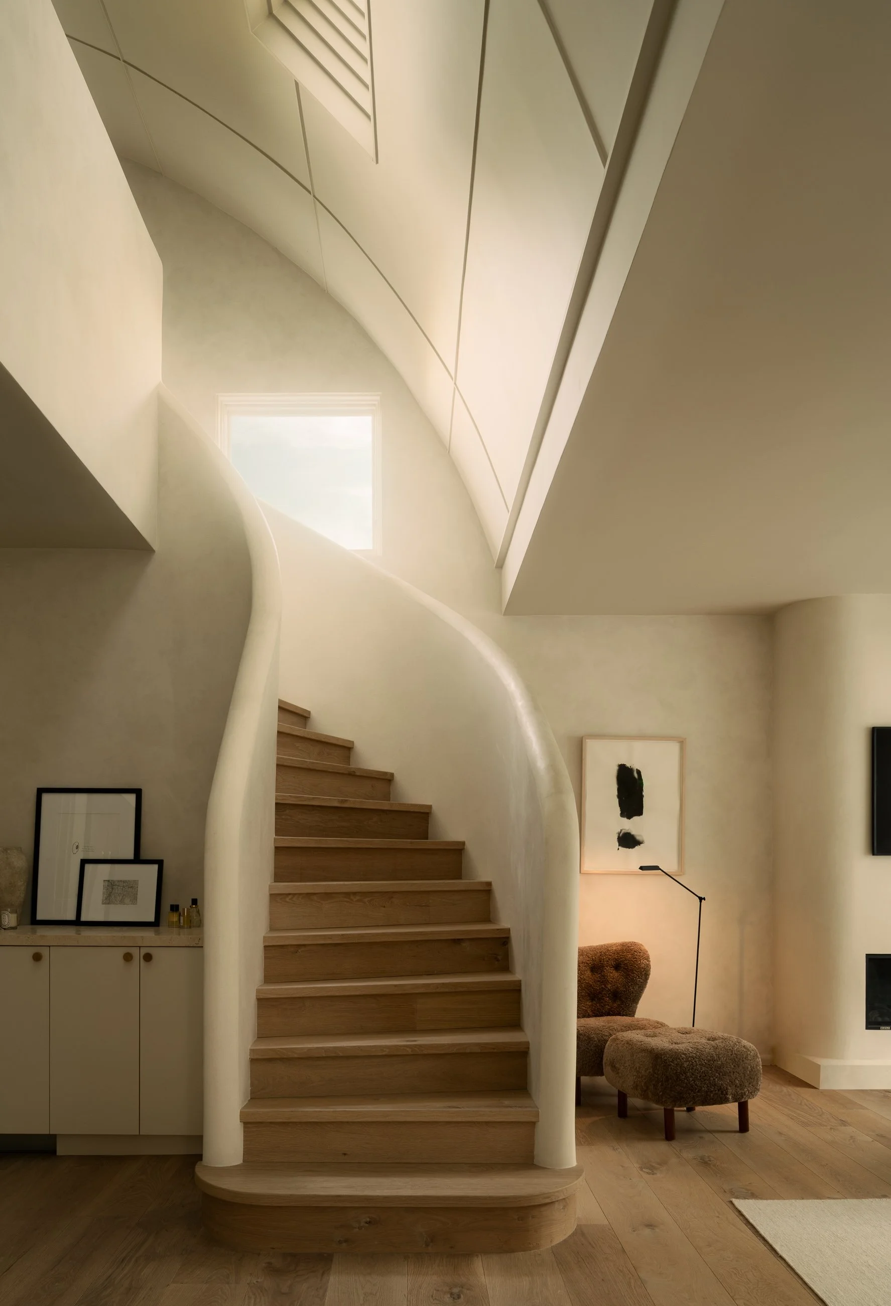 Sculptural curved staircase with smooth plaster walls and warm contemporary detailing, completed by JBurton General Contractor for a luxury home renovation in Benedict Canyon, Los Angeles.