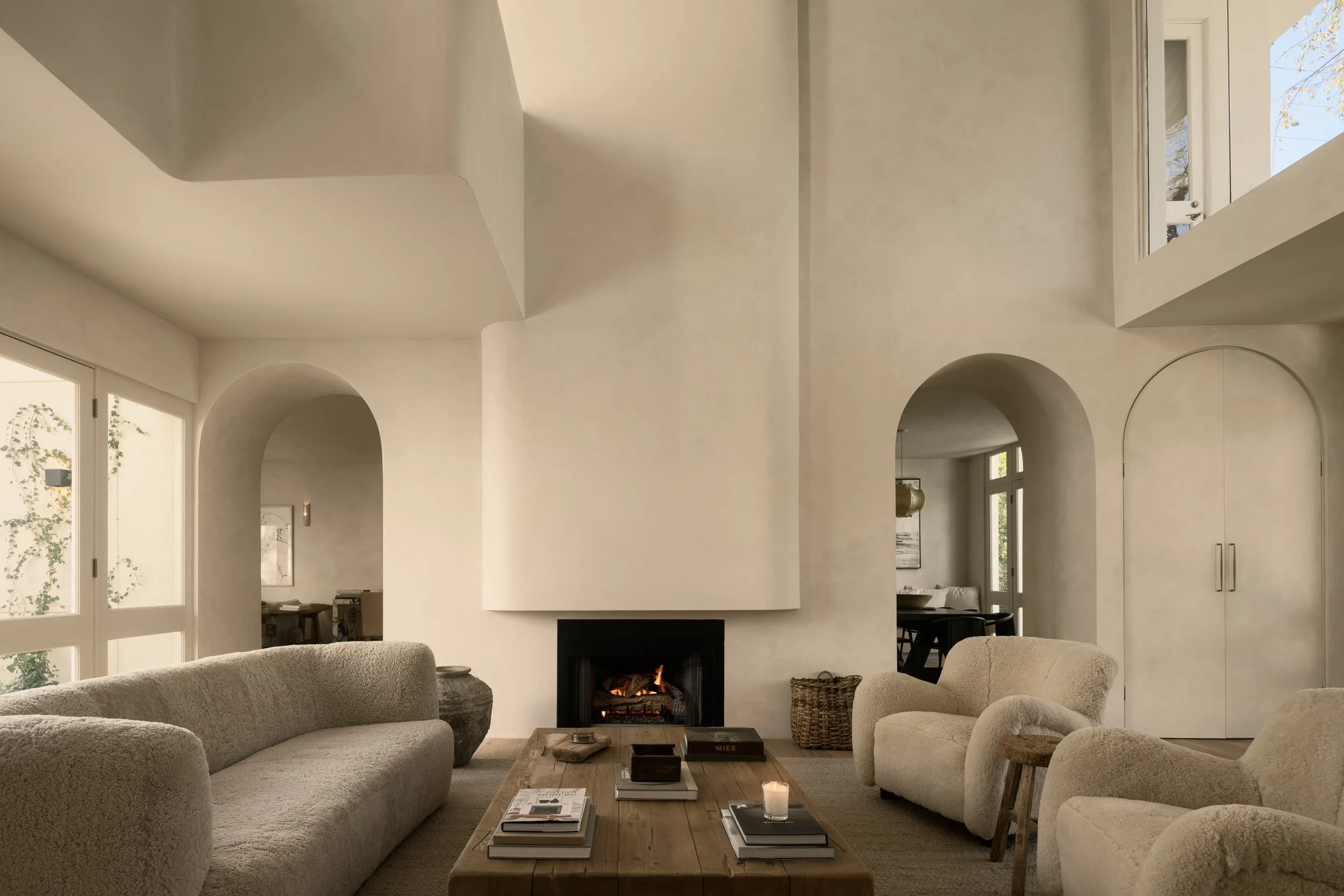 Living room with a custom plaster fireplace, arched openings, and contemporary furnishings, completed by JBurton General Contractor for a luxury home remodel in Benedict Canyon, Los Angeles.