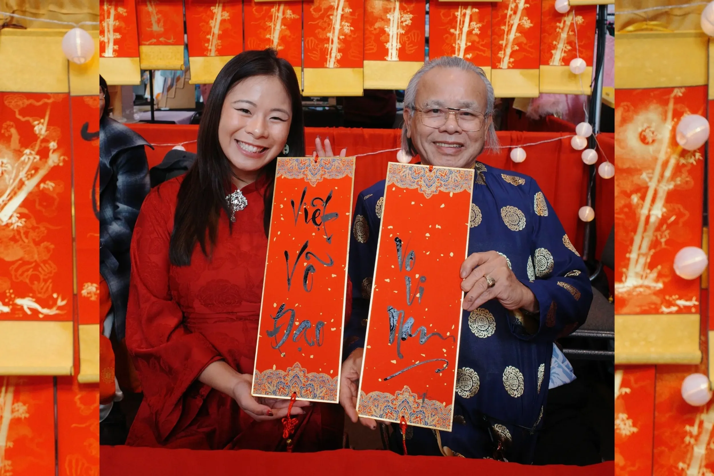 Linh Nguyen and her father smiling and holding up their Vietnamese calligraphy scrolls at Tết Seattle 2025, surrounded by orange and gold decorations.