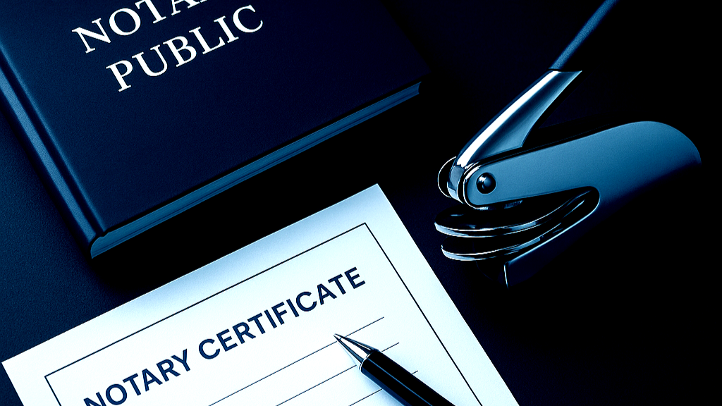 A notary public book, a stapler, and a blank notary certificate form with a pen on top.