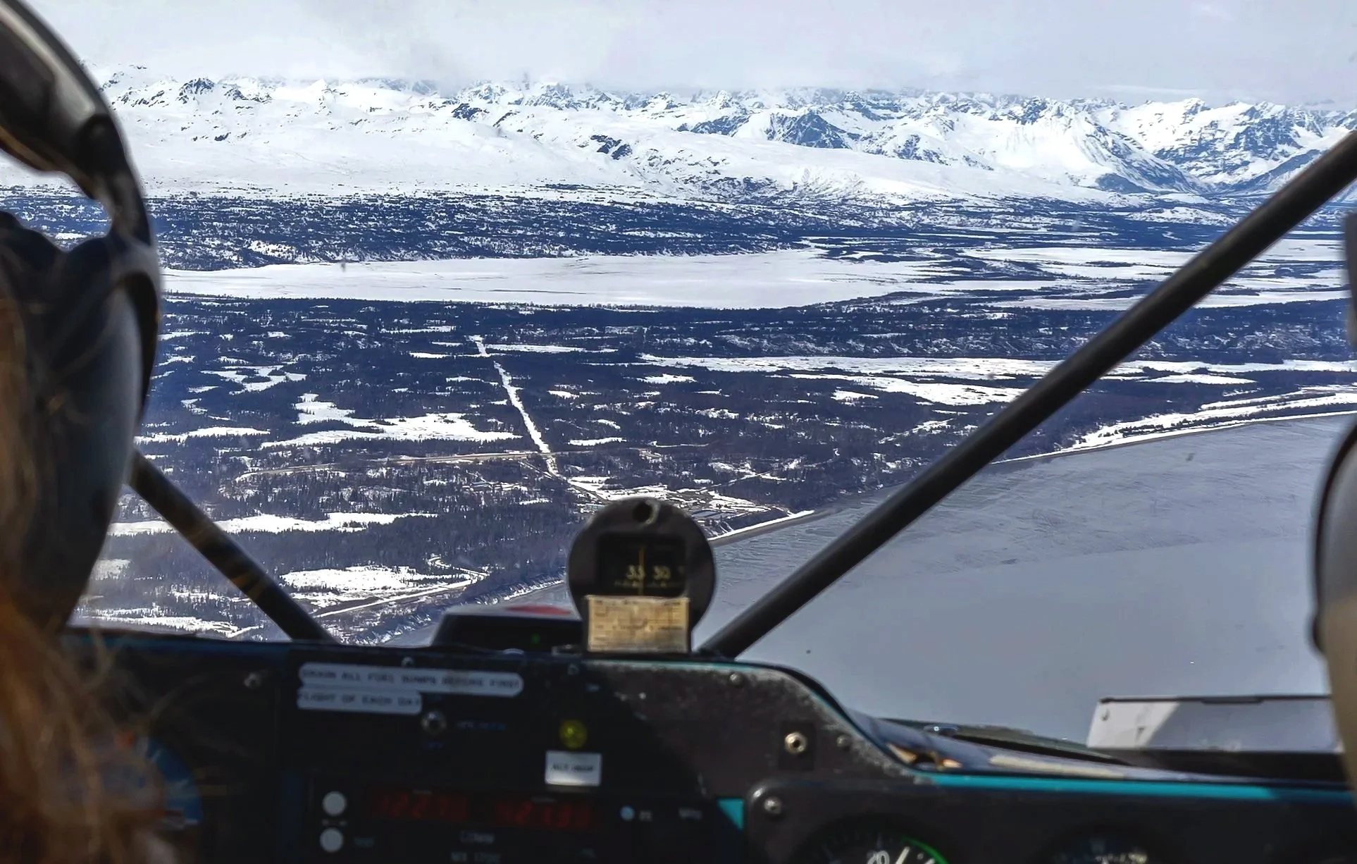 Aerial view of snow-covered mountains and landscape from an aircraft cockpit during flight.