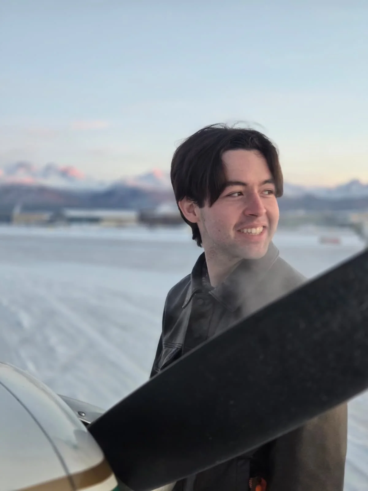 Close-up of a pilot under a wing with a blurred background.