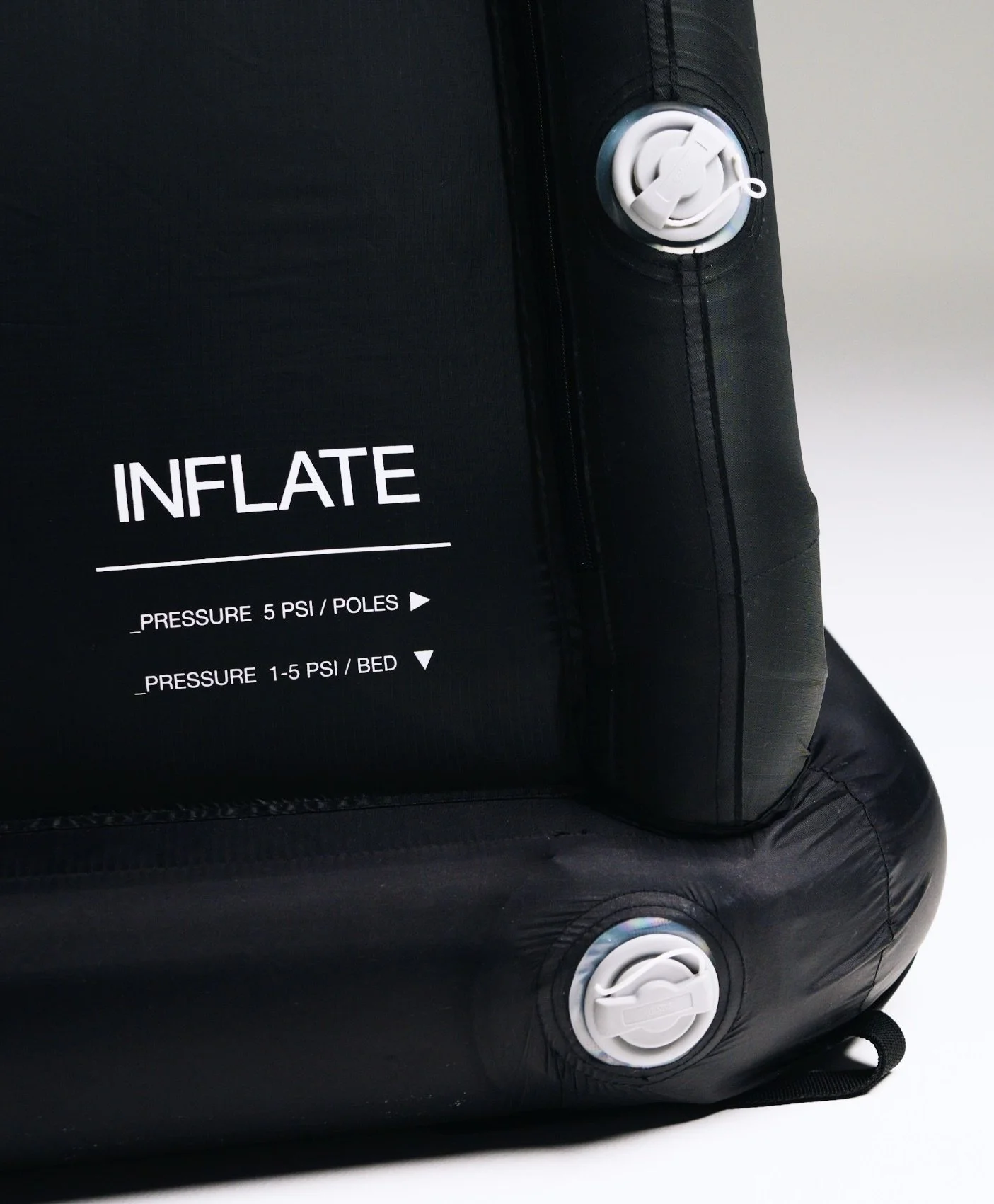 A black inflatable air mattress with white valve and pressure instructions label.