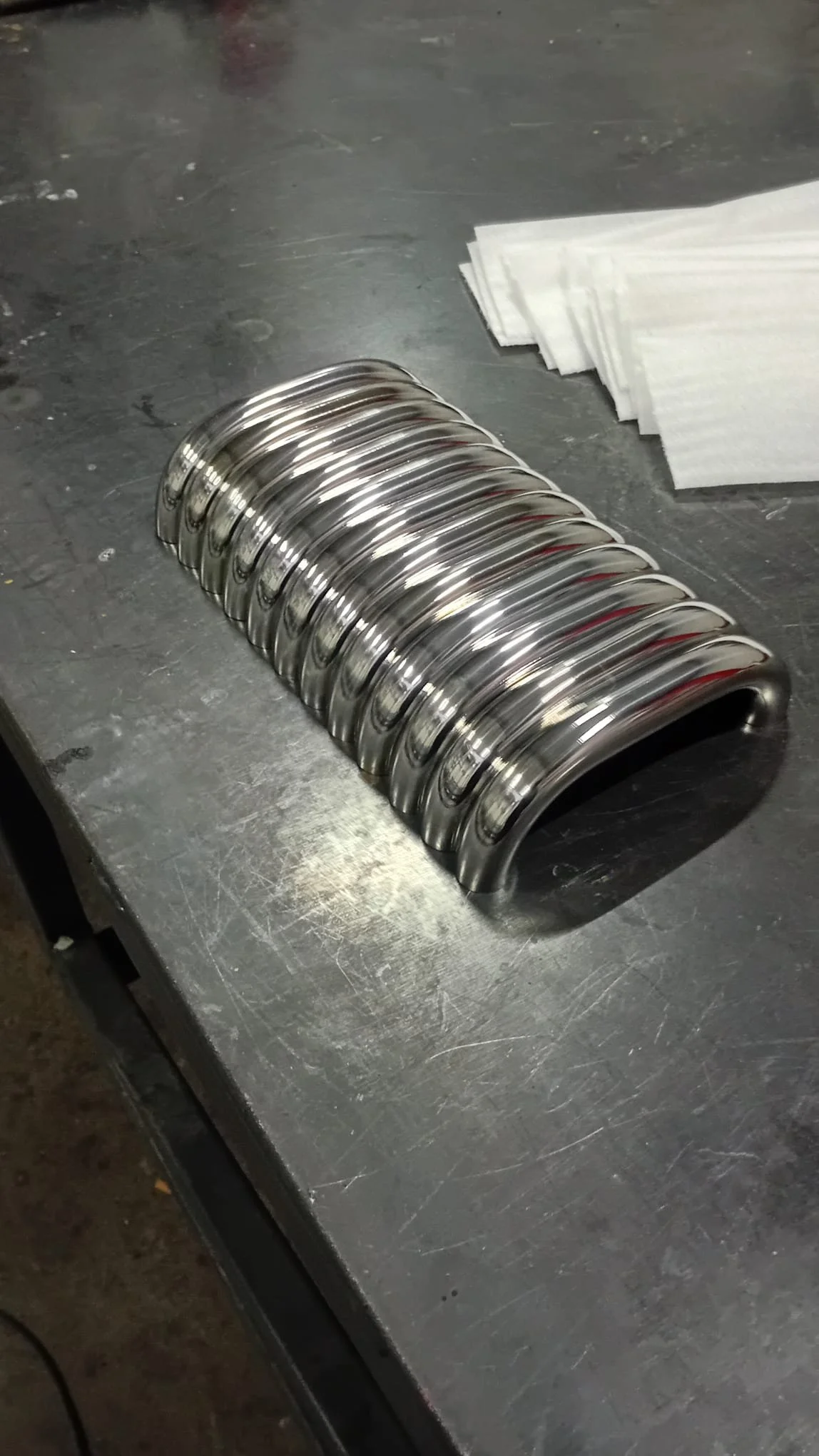 Düzenlenmiş, parlak metal yay, metal masanın üzerinde, yanında kağıtlar var.