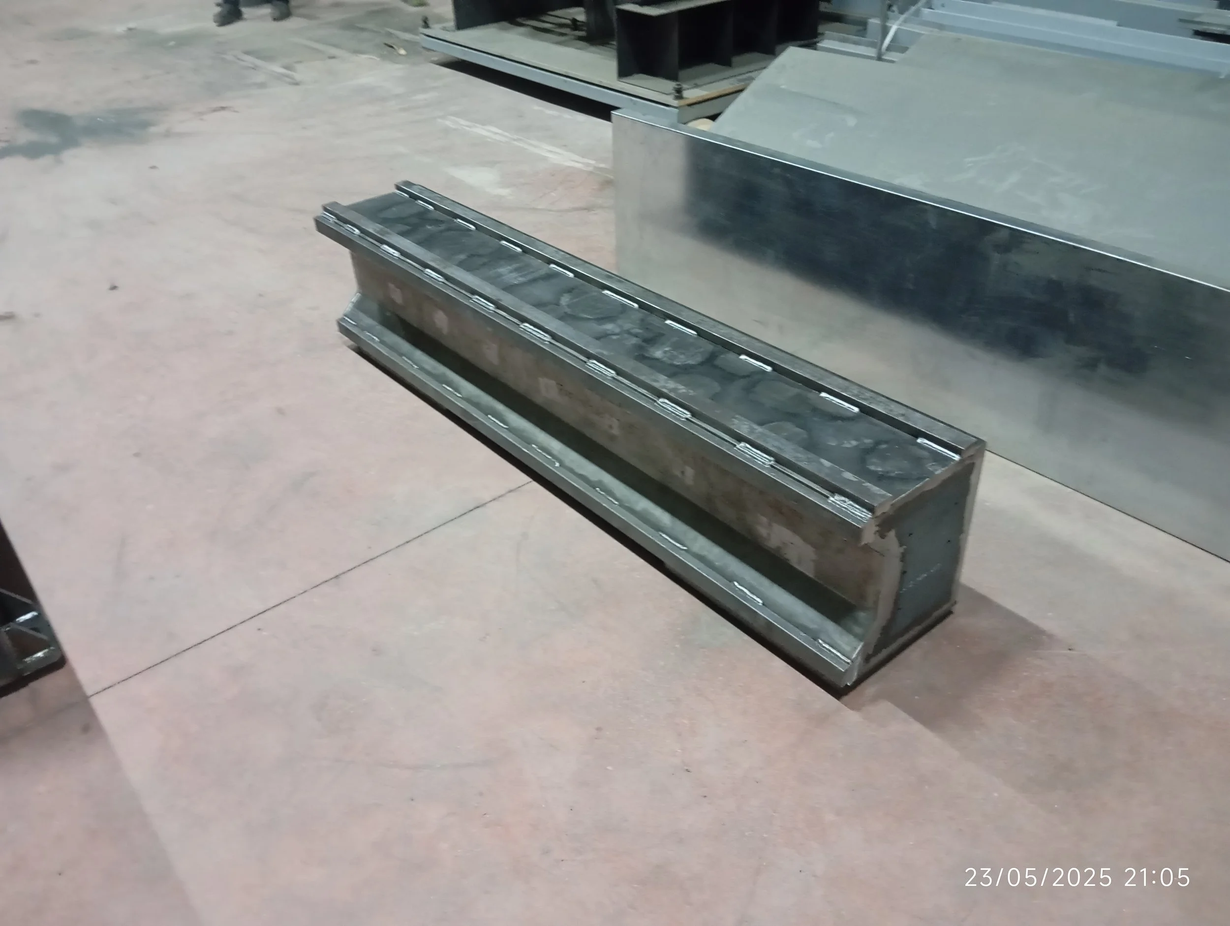 Metal yapımında kullanılan büyük bir metal parça ve yapım aşamasında olan başka metal parçaları metal bir zeminde duruyor.