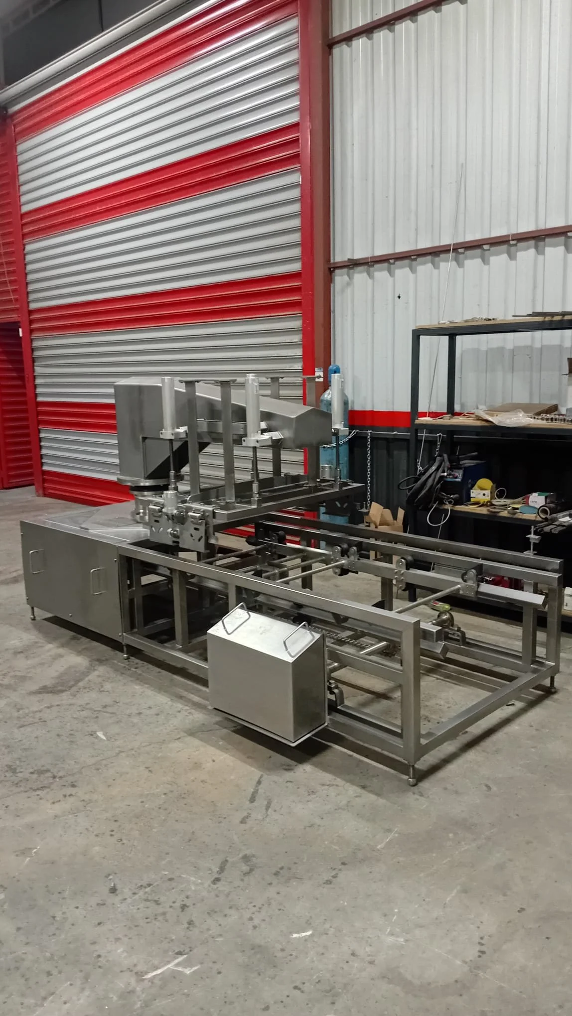 Endüstriyel makina, fabrika veya atölyede metal yapılar ve makineler. Red ve gümüş renkli metal çerçevede çeşitli mekanik parçalar. Arka planda kırmızı ve gri metal kaplı duvarlar.