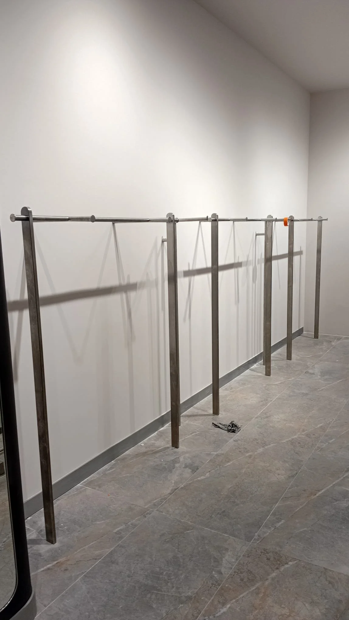 Beyaz duvara karşı metalten bir elbise askılığı.