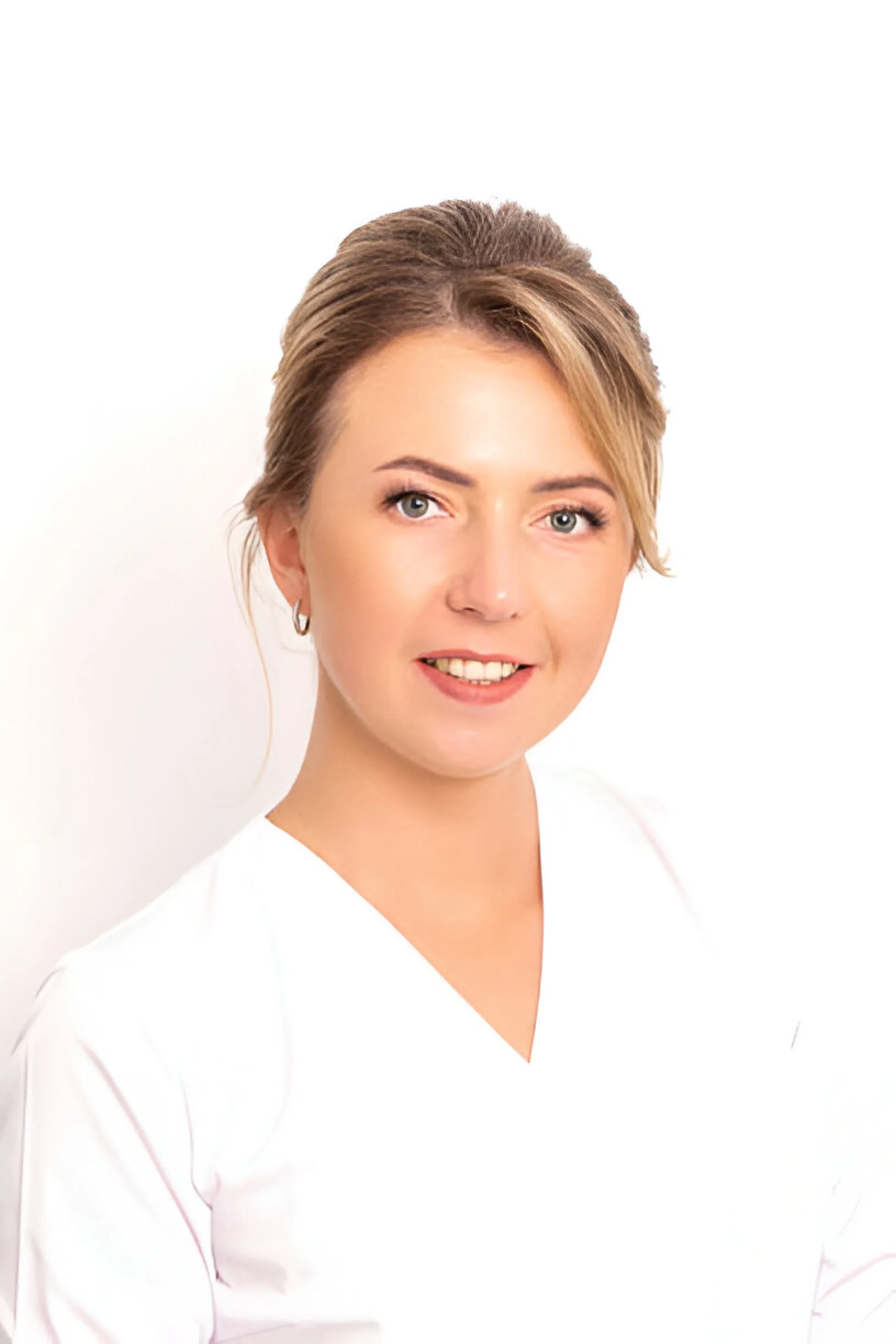 Portrait of a woman with short light brown hair, blue eyes, and wearing a white top, smiling slightly against a plain white background.