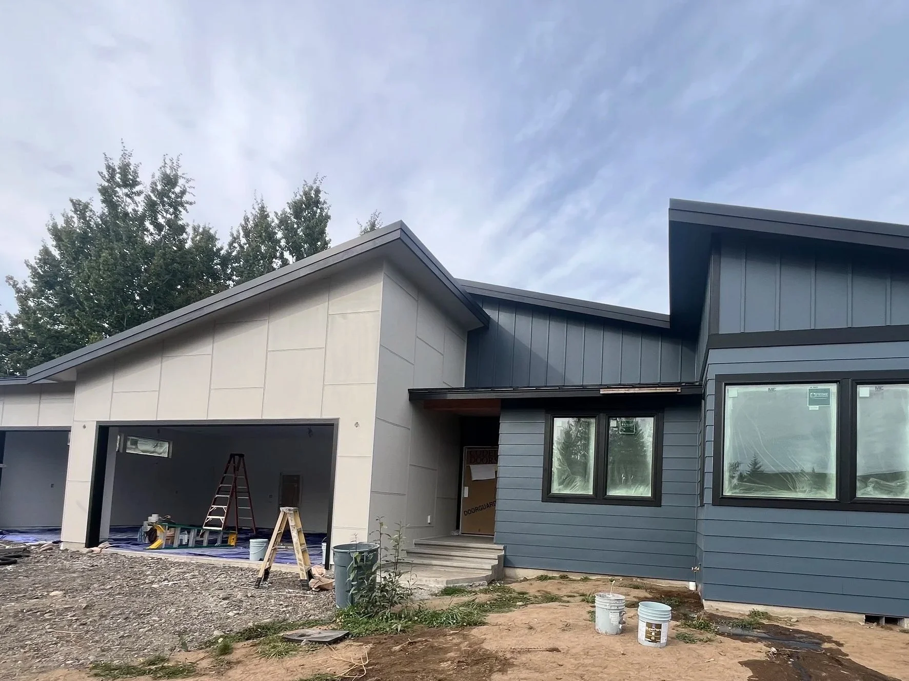 Contemporary home exterior with gray lap siding and standing seam metal roof nearing completion