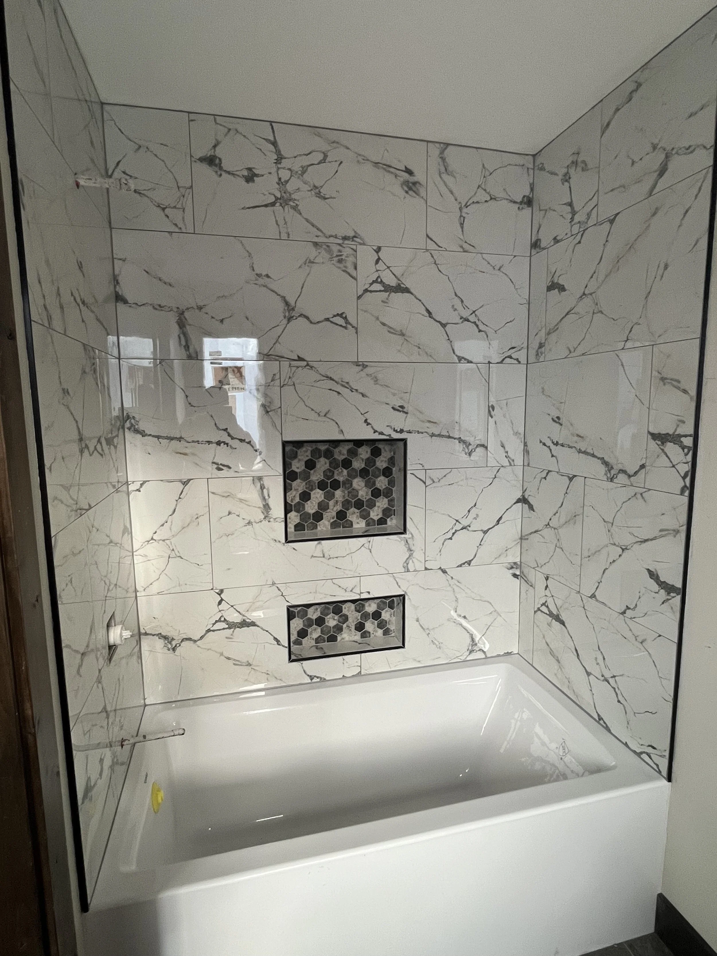 Marble-look porcelain tub surround with hexagon mosaic niches