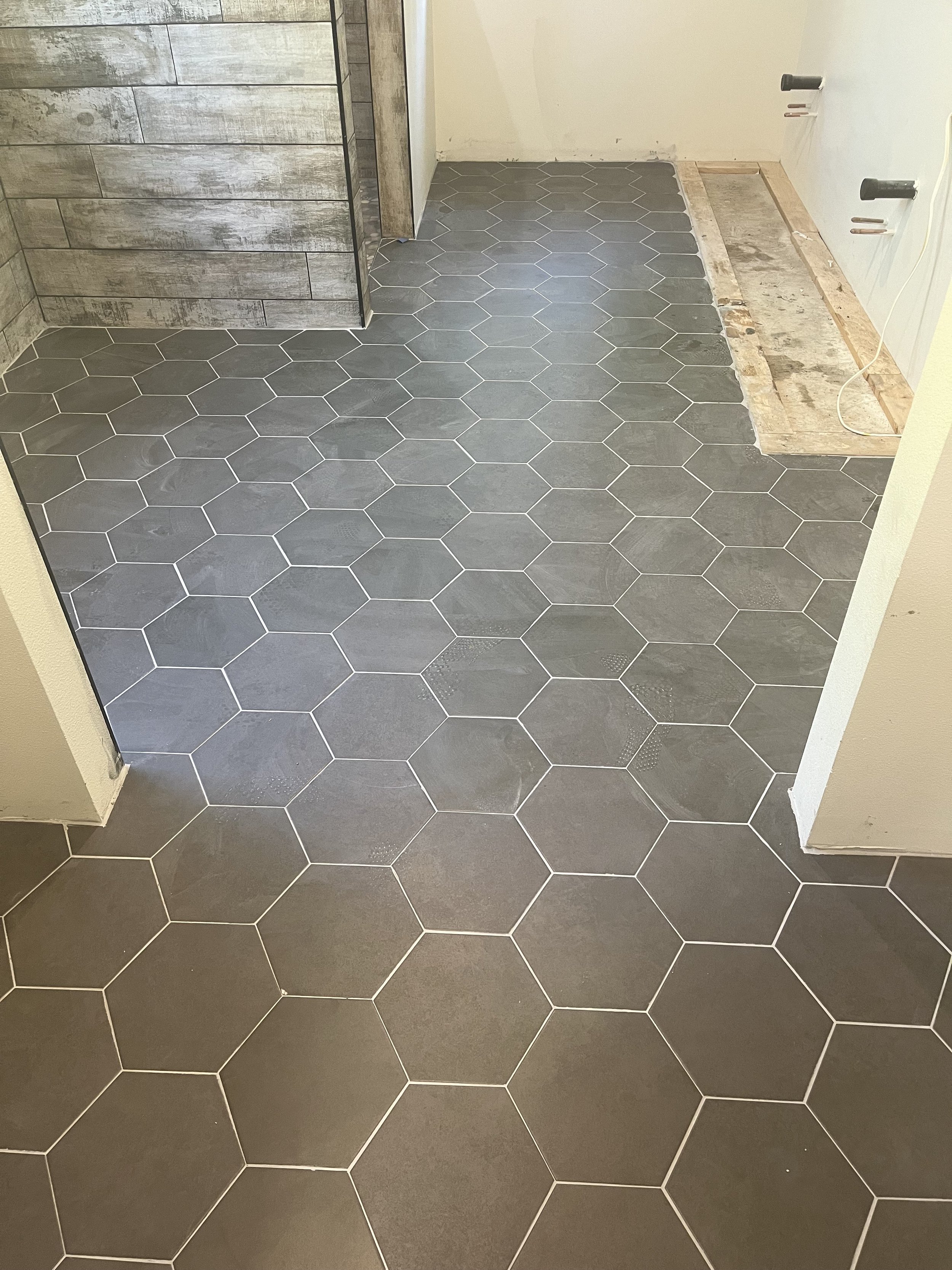 Large-format hexagon tile floor with wood-look plank accent wall in Whatcom County bathroom remodel