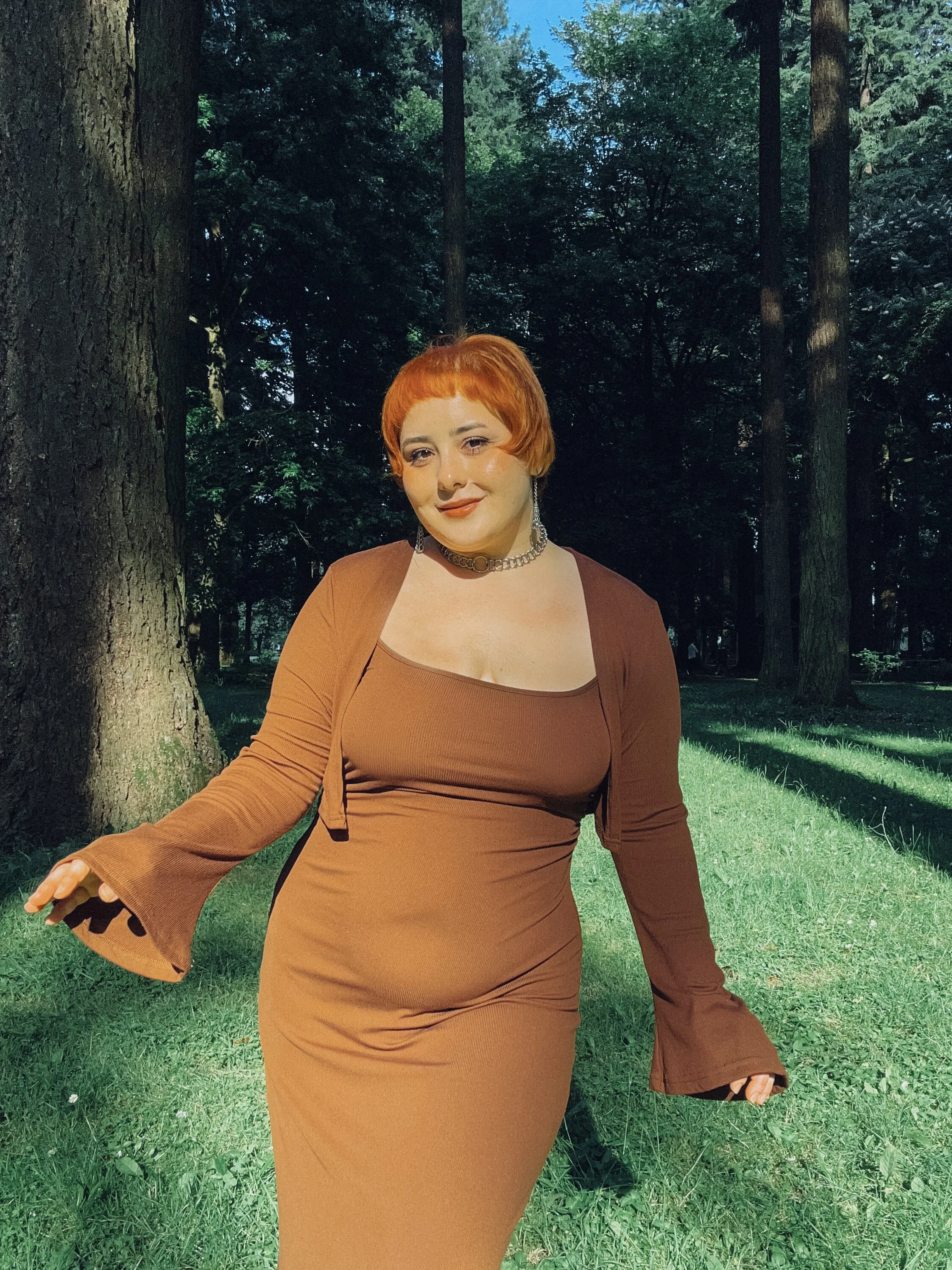 artist image showing Revolutionary Grl wearing a brown dress and shawl in the forest