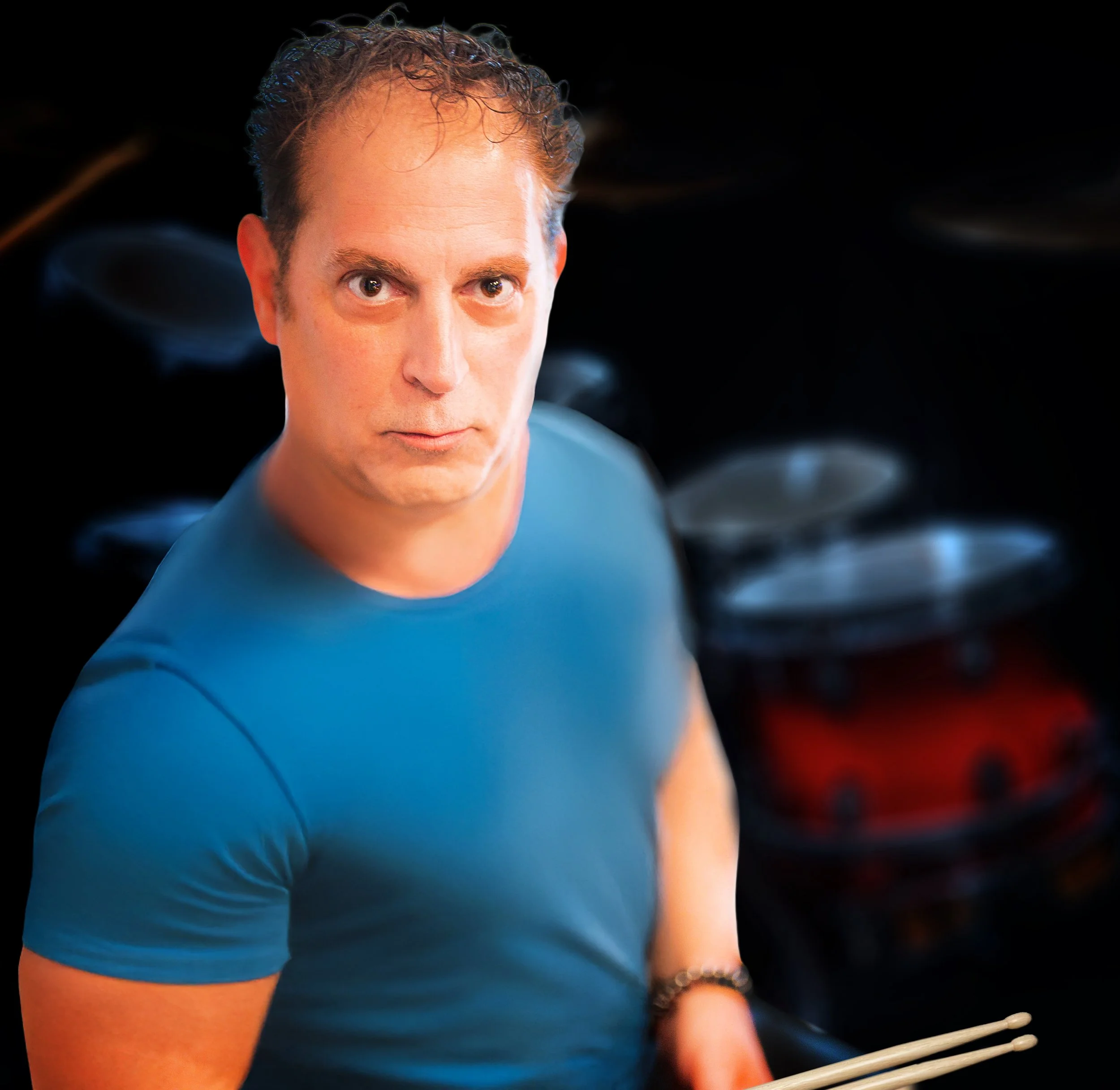 A woman playing the drums in a music venue with a large rock and roll sign on the brick wall behind her.