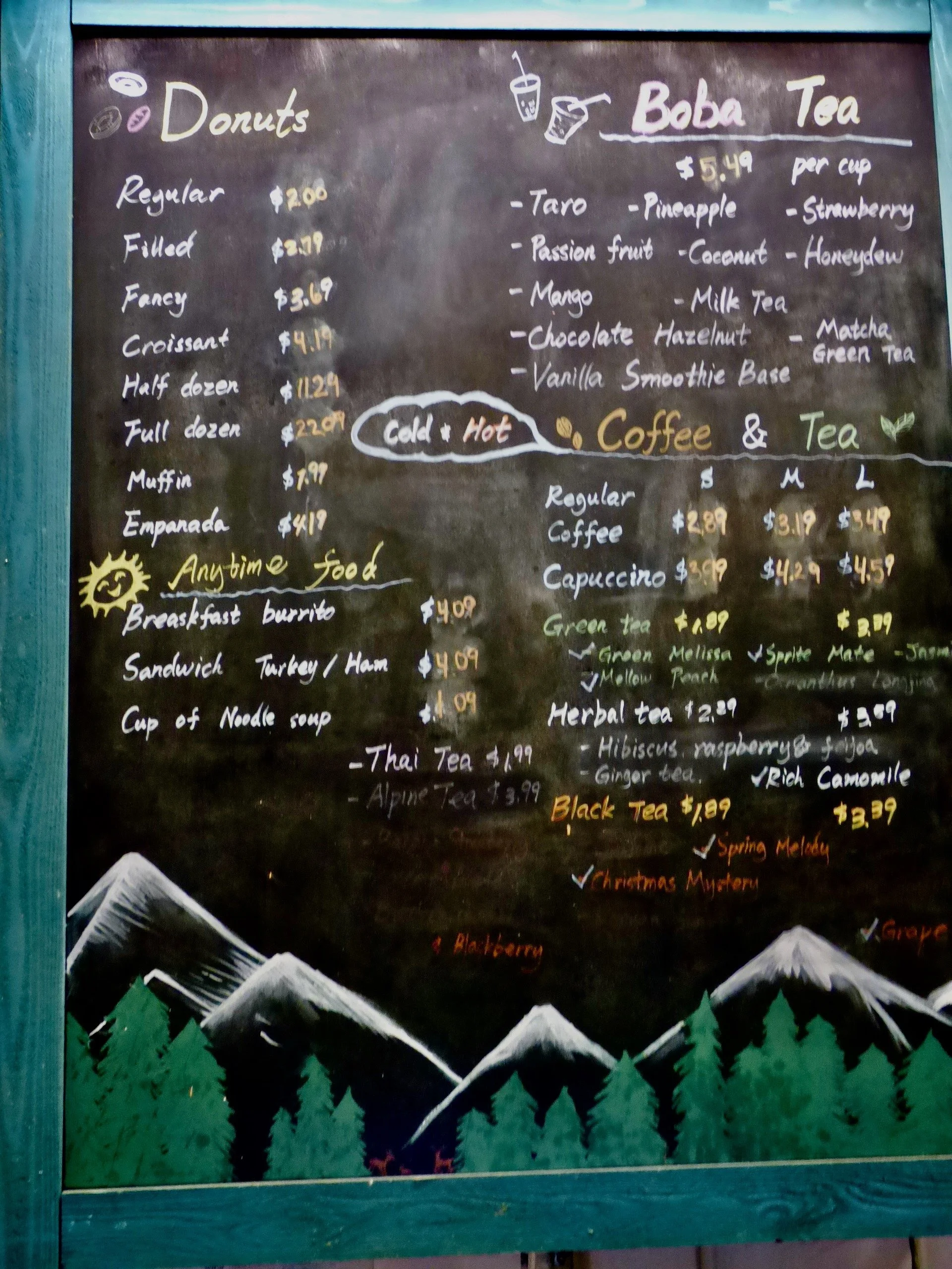 Menu board with sections for donuts, boba tea, coffee, and tea. Prices listed for each item, with decorative mountains and trees at the bottom at PF Donut Shop, Denver, CO 80205.