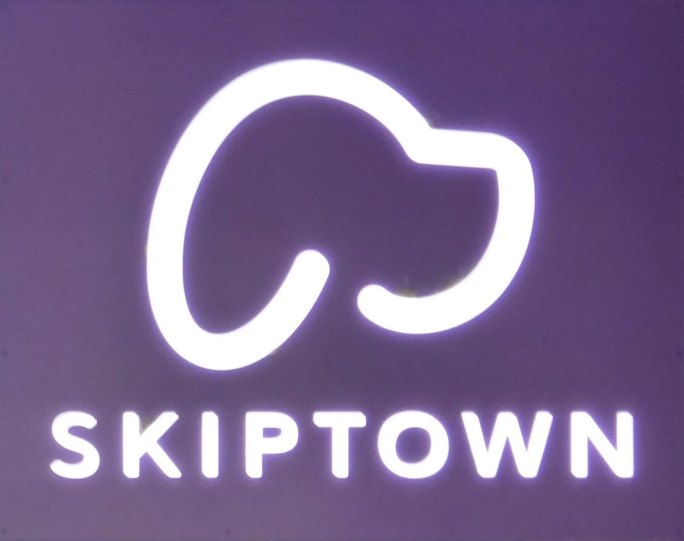 Neon sign with a stylized whale tail and the word "Skiptown" beneath it at Skiptown, Denver, CO 80205.