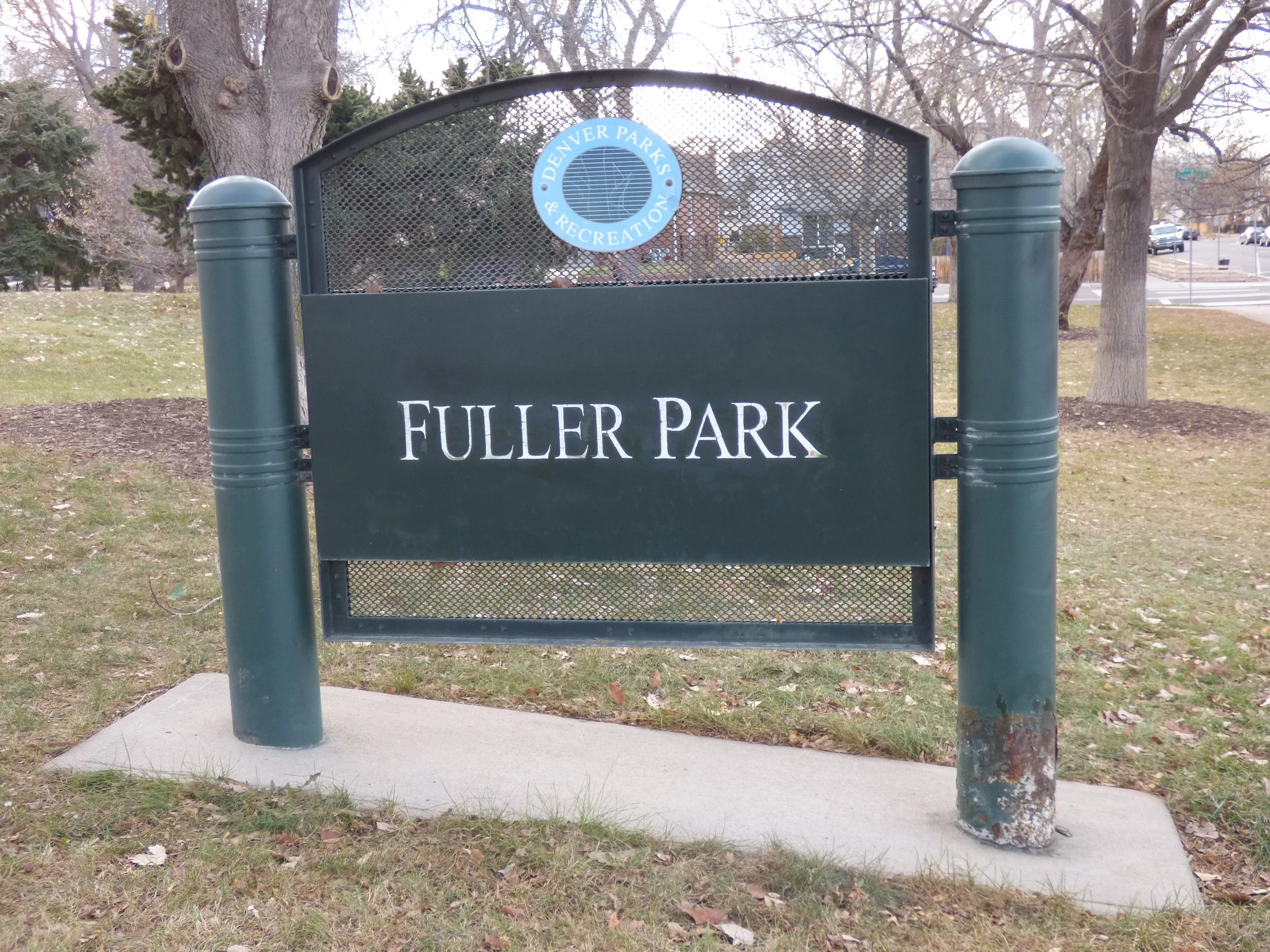 Sign at Fuller Park with Denver Parks & Recreation logo on top, stating 'FULLER PARK' in white text on a dark green background at Fuller Park, Denver, CO 80205.