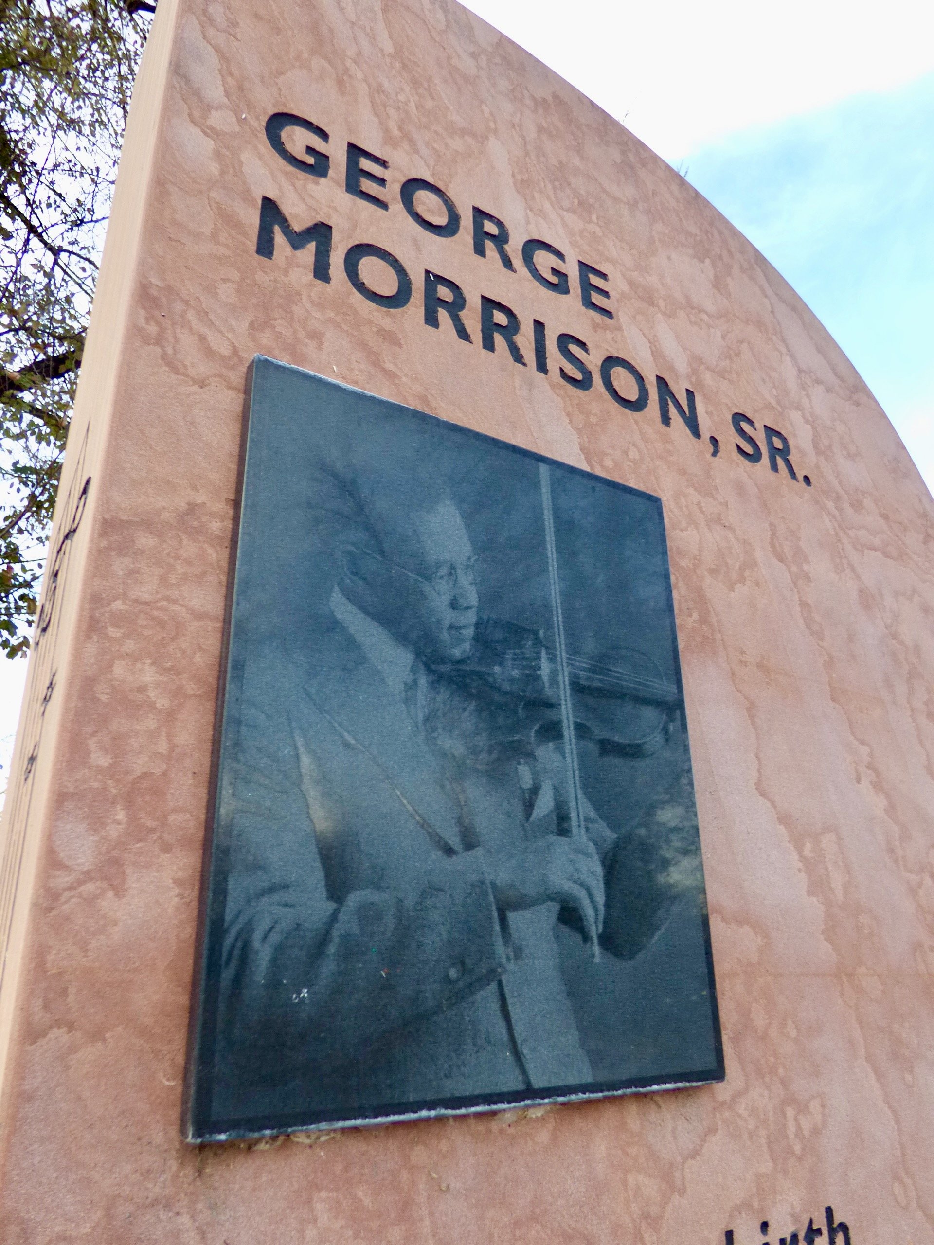 A memorial sign for George Morrison Sr., with a black and white photo of him playing the violin at George Morrison Sr. Park, Denver, CO 80205.