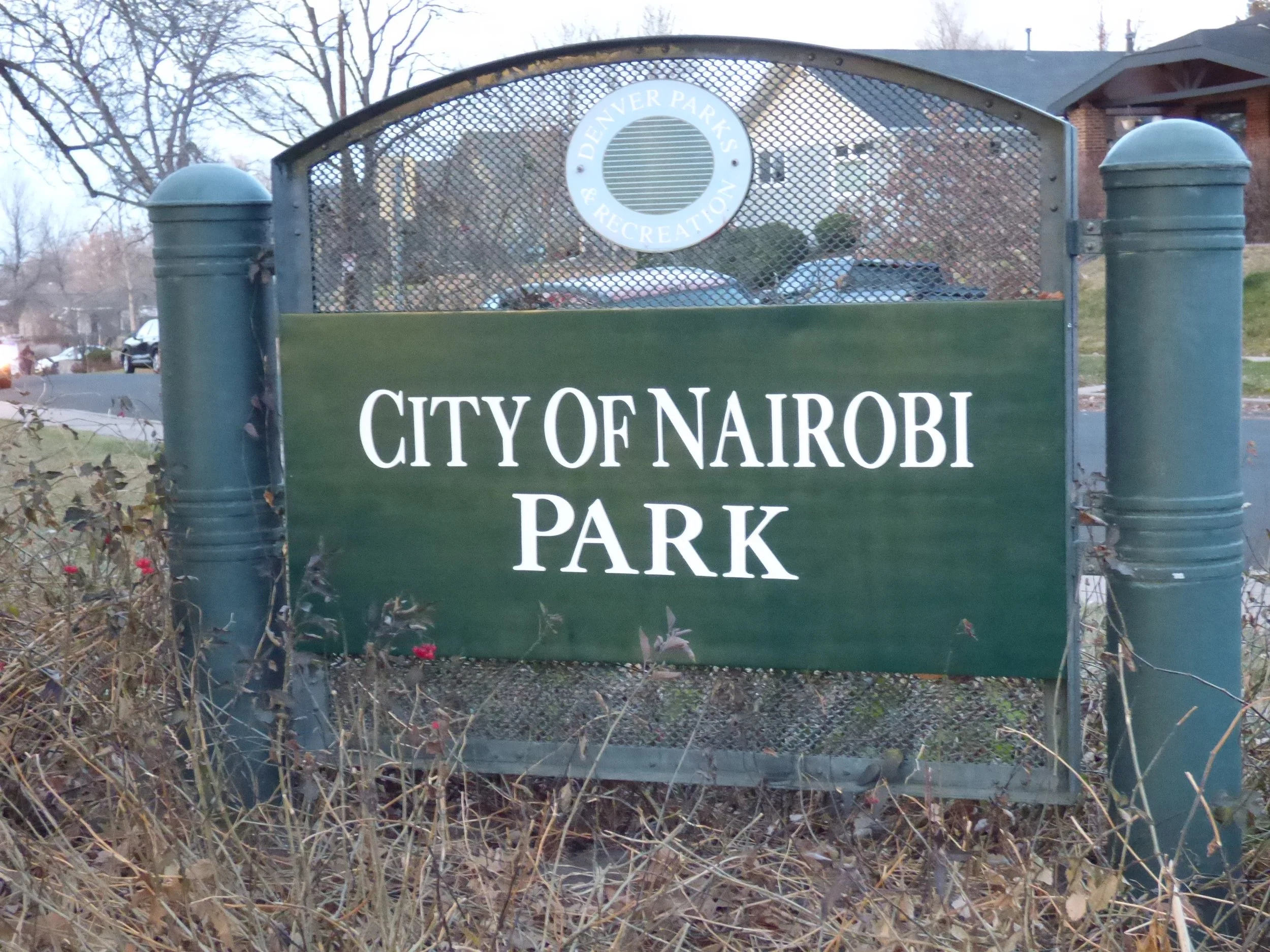 Green sign with white text reading "City of Nairobi Park" and a circular emblem at the top that says "Denver Parks & Recreation".