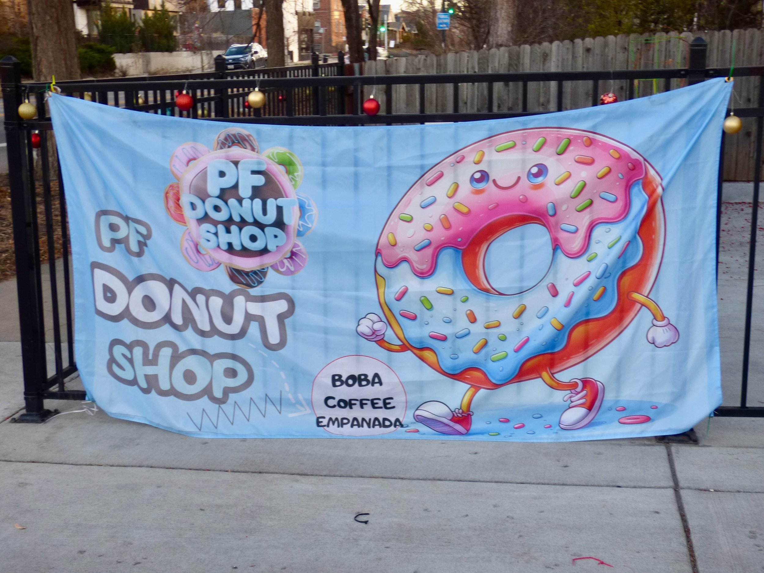 Decorative banner for PF Donut Shop featuring a cartoon donut with colorful icing and sprinkles, smiling and walking, with text indicating the shop offers boba, and coffee at PF Donut Shop, Denver, CO 80205.