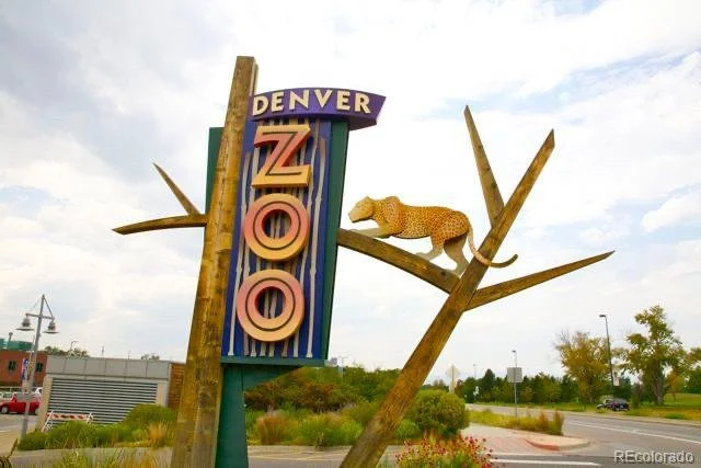 Sign for Denver Zoo with a yellow leopard statue on a tree branch at Denver, CO.