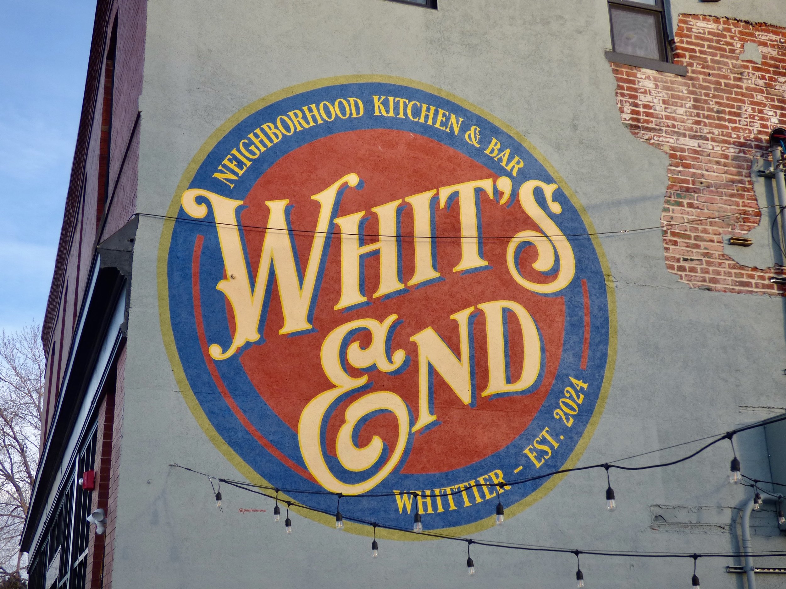 Large mural on the side of a building advertising Whit's, a neighborhood kitchen and bar in Whittier, established 2024 at Whit's End, Denver, CO 80205.
