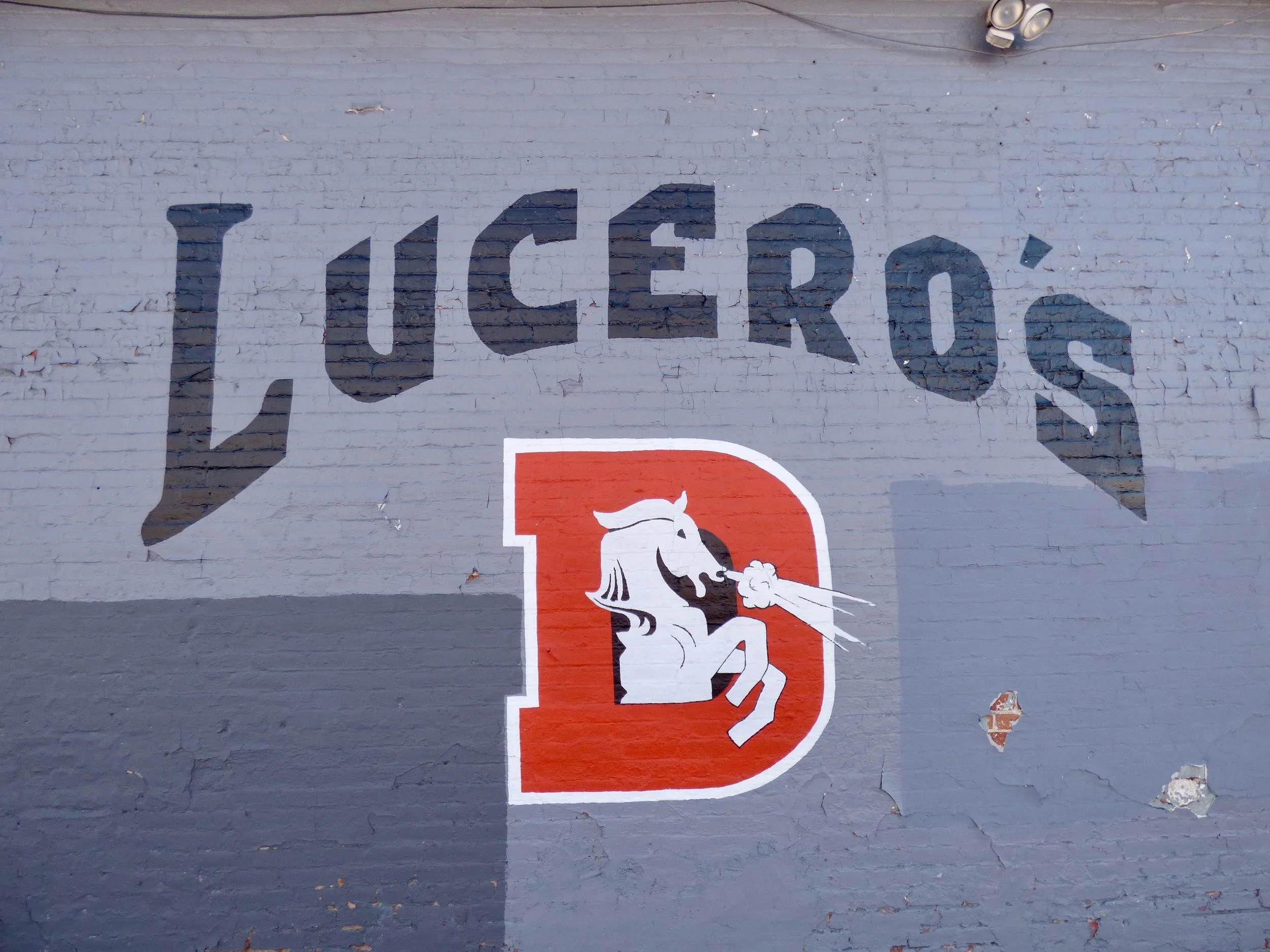 Wall mural with the word 'LUCE' as part of the word 'LUCE ROD'S' painted above a stylized horse logo in red, black, and white, with a smoking nostril
