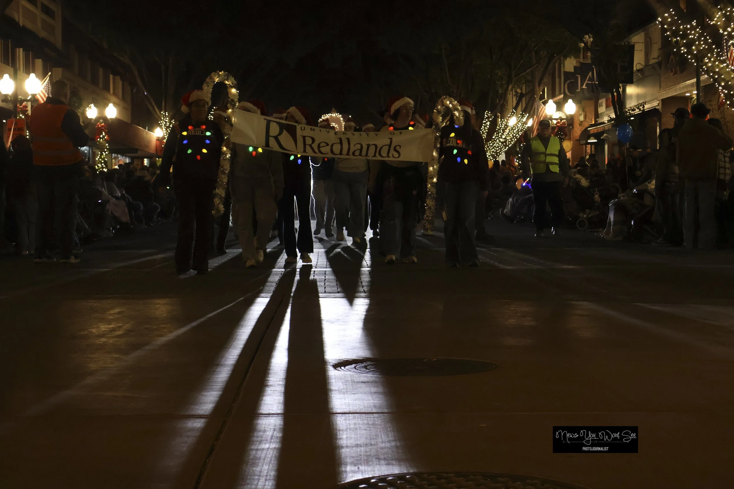  Members og the University of Redlands carry their sign in front of their float in the annual Christmas parade hosted by the Kiwanis Club of Redlands on Saturday, Dec. 6, 2025. (Photo by Brian Spears, Redlands Collective News) 