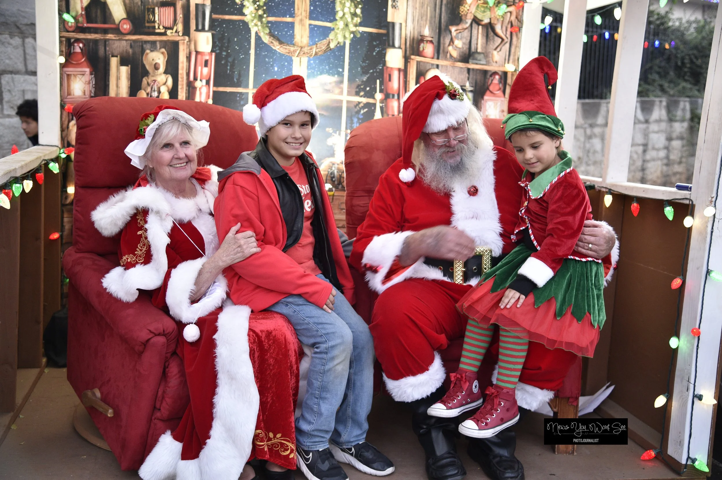  Jamil and Tristan Rochford sit on Mr. and Mrs. Claus’ laps at The Burrage Christmas drive-thru. Dec. 14, 2025 ( Photo by Brian Spears, Redlands News Collective) 