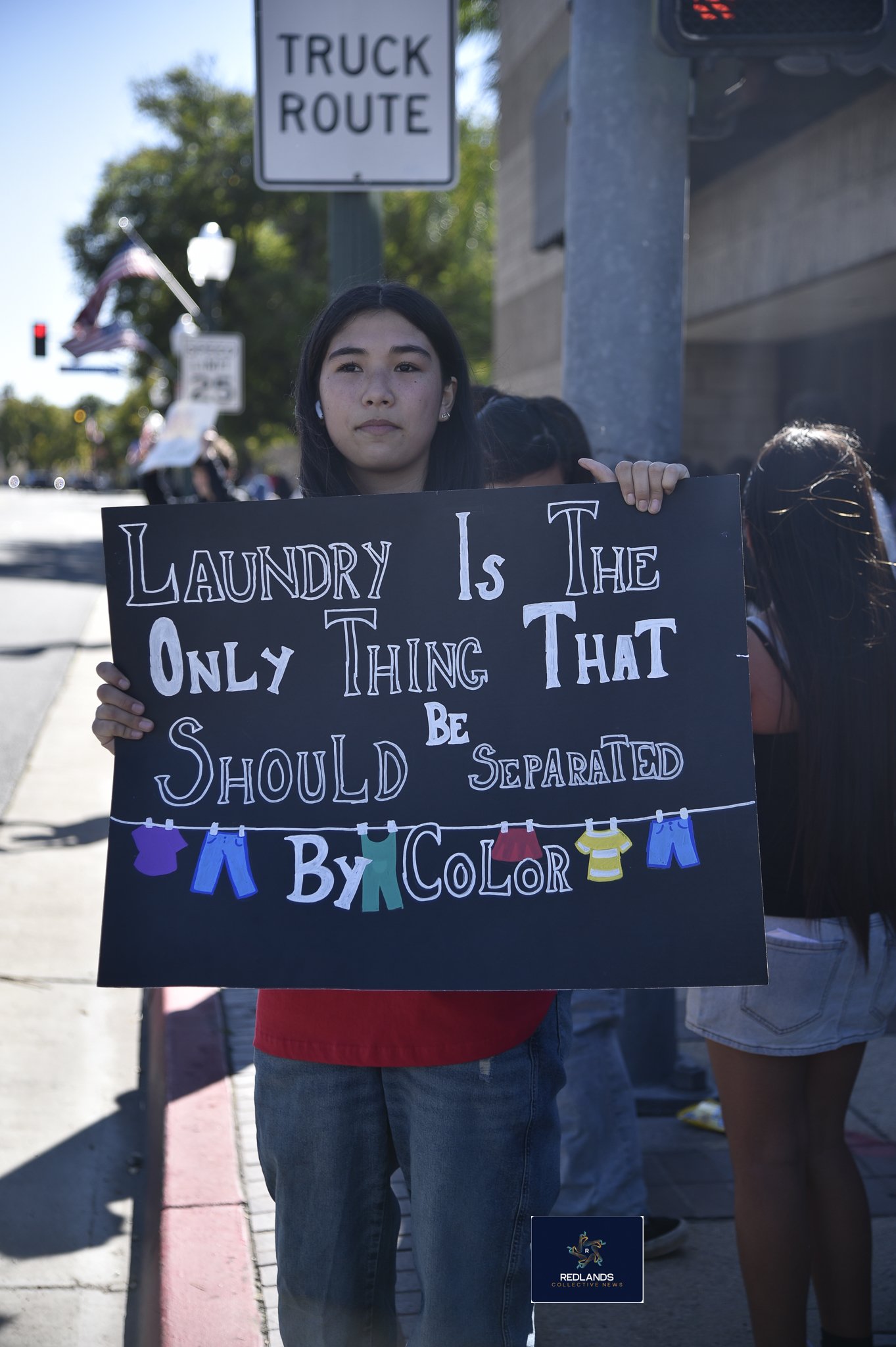  Ellie Kanshalge holds a sign against ICE Feb. 13, 2026 in downtown Redlands (Photo by Brian Spears, Redlands News Collective)  